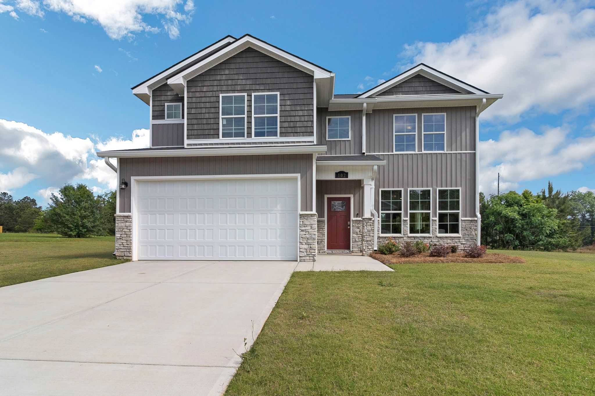 Modern two-story home exterior in Ivy Glen Perry GA by Evermore Homes with gray siding red door attached garage and manicured lawn