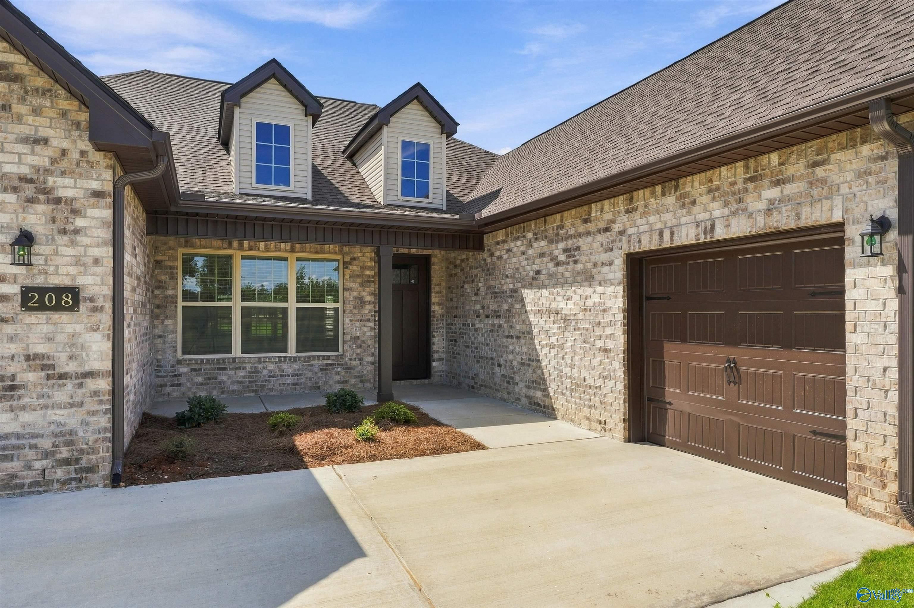 Brick front exterior with dormer windows and 3-car garage at Davidson Homes The Valencia in Riverton Preserve, Huntsville, Alabama