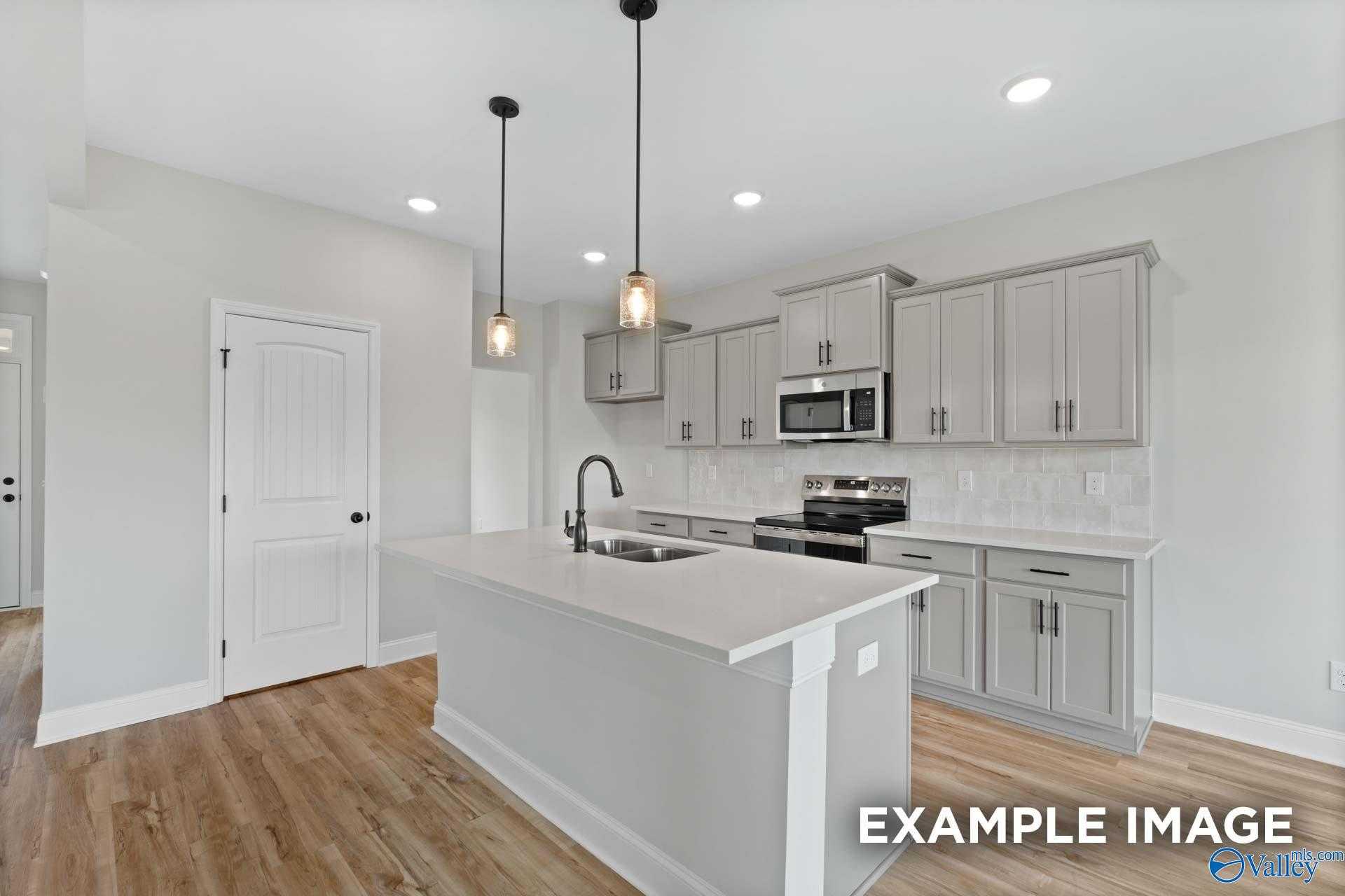 Modern open-concept kitchen with light gray cabinets, center island, stainless appliances in The Shelby A, Davidson Homes, Athens AL