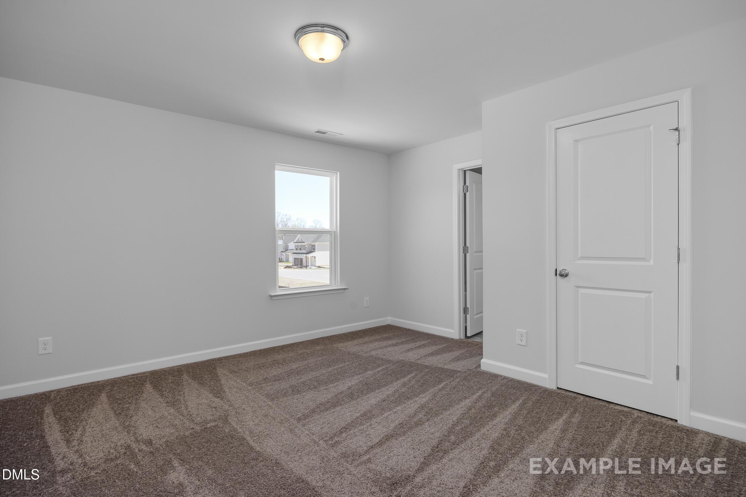 Bright, carpeted bedroom with neutral walls in The Gavin A floor plan by Davidson Homes in Gregory Village, Lillington, NC.