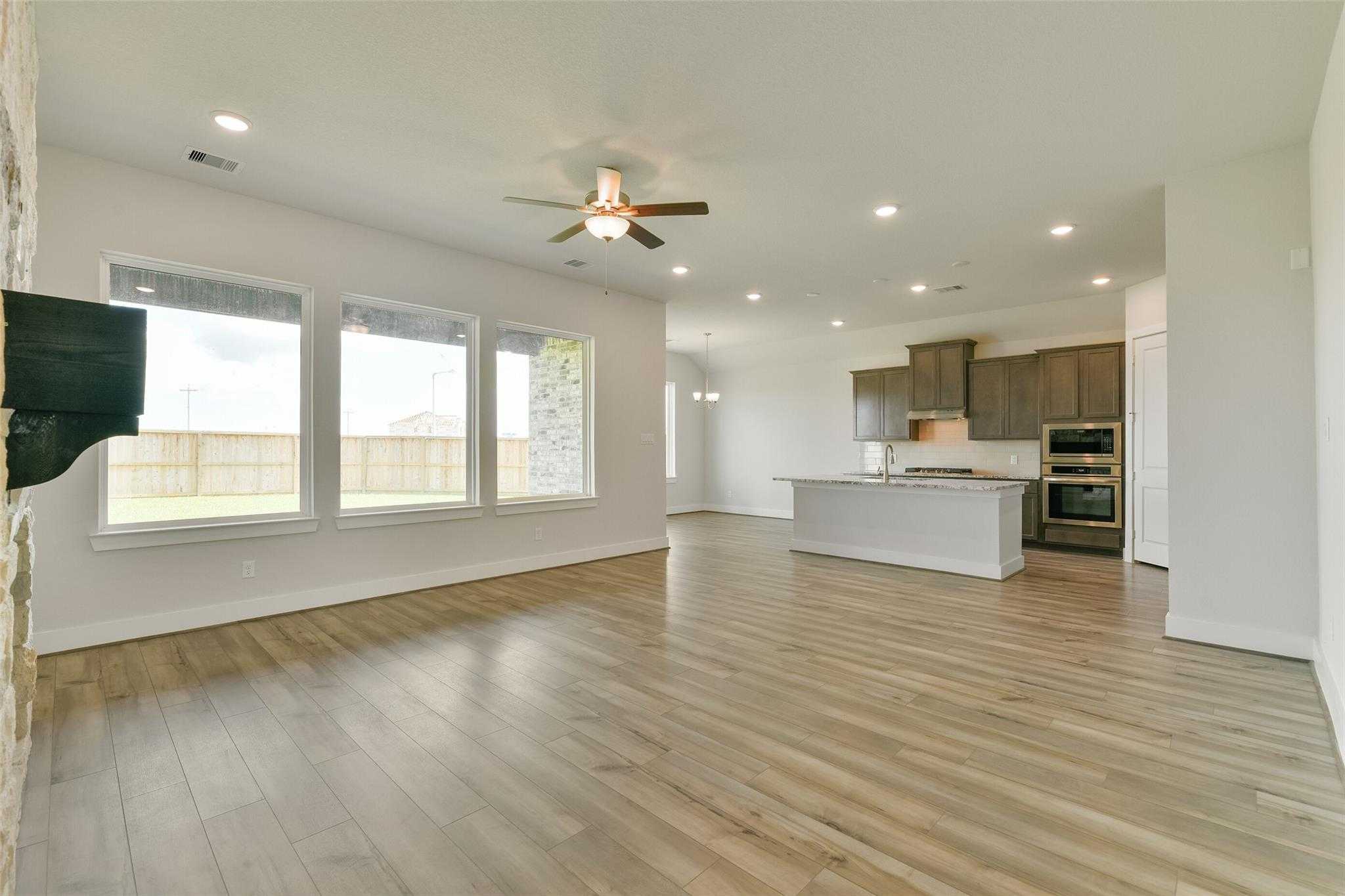 Open-concept living kitchen with hardwood floors, large windows to backyard, stainless appliances in Davidson Homes The Edward A, Lago Mar, Texas City