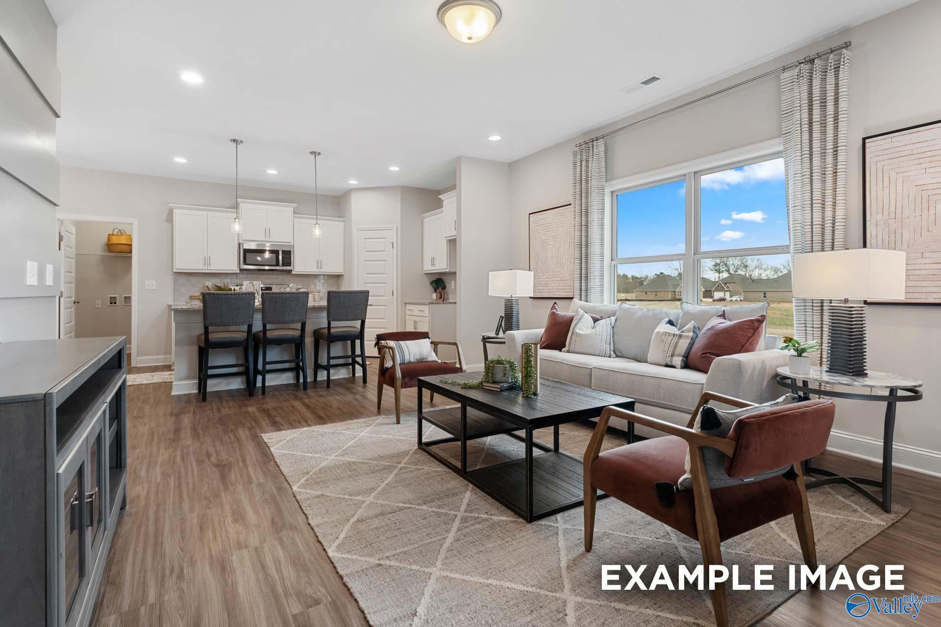 Open-concept living room and kitchen with white cabinets and bar seating in Davidson Homes Camilla C, Hartselle, Alabama