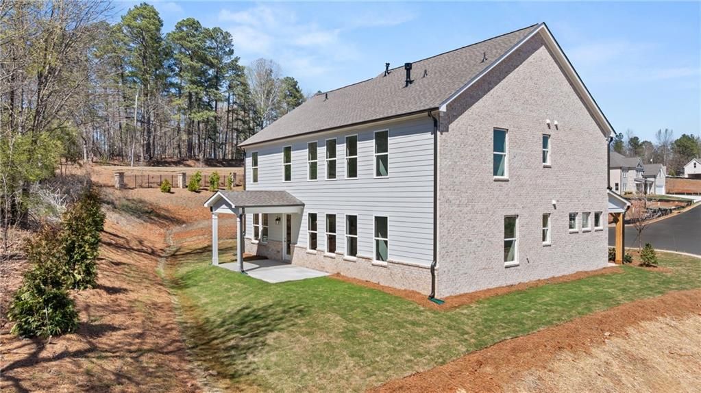 Side view of The Danbury C two-story home with brick siding and covered patio in Melody Lakeside Estates, Buford, Georgia.