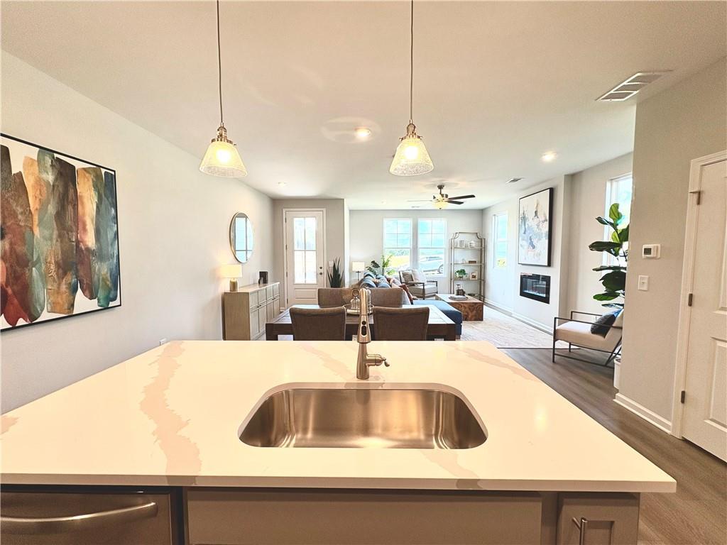 Modern open-concept kitchen with quartz island, stainless sink, and adjacent living room in The Monroe A, Emerson, Georgia