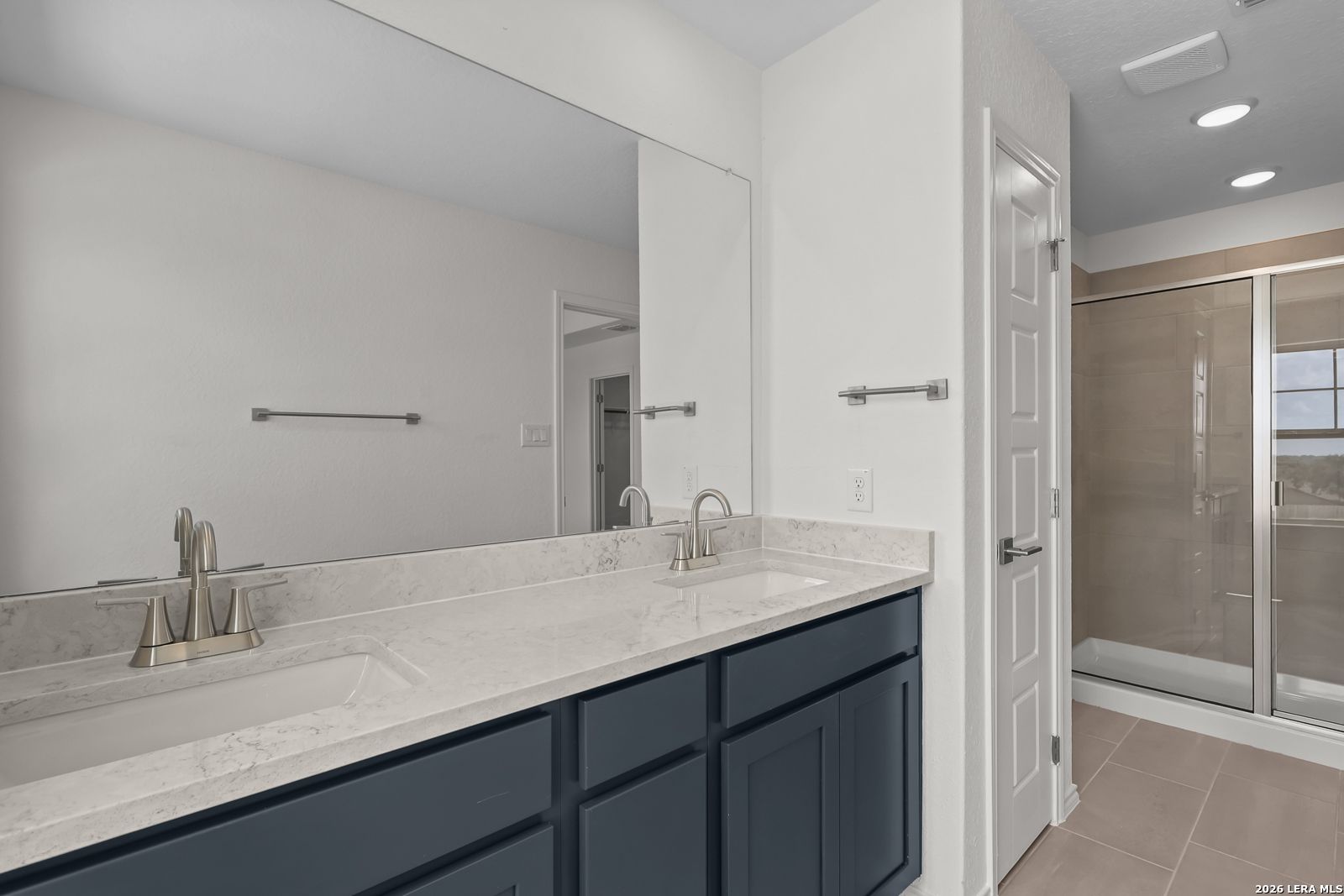 Dual vanity with navy cabinets and quartz countertops in The Gillian C floor plan by Davidson Homes, San Antonio, Texas.