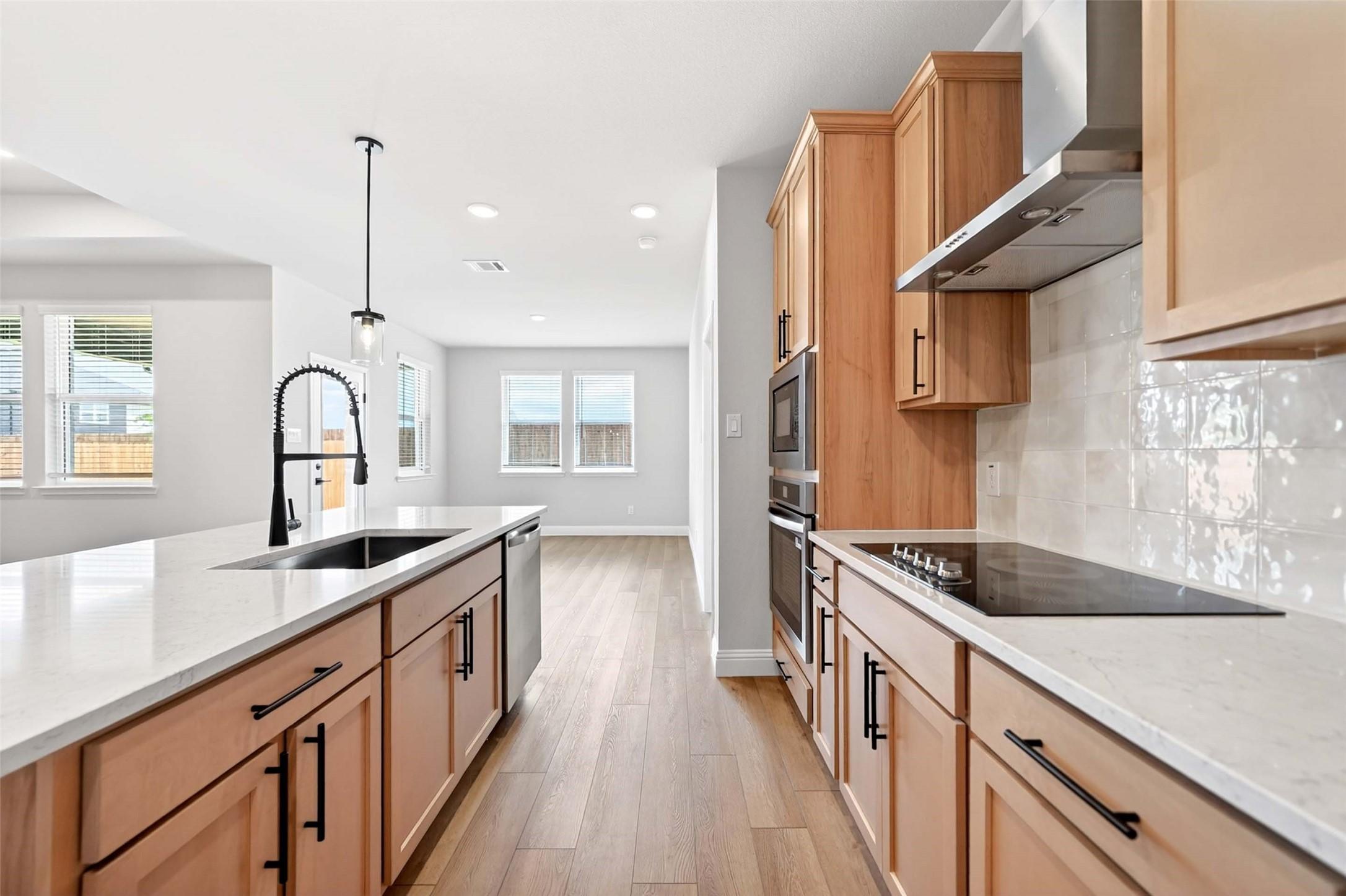 Modern kitchen with light wood cabinets, white quartz countertops, and stainless appliances in The Holly C plan, Anna, TX.