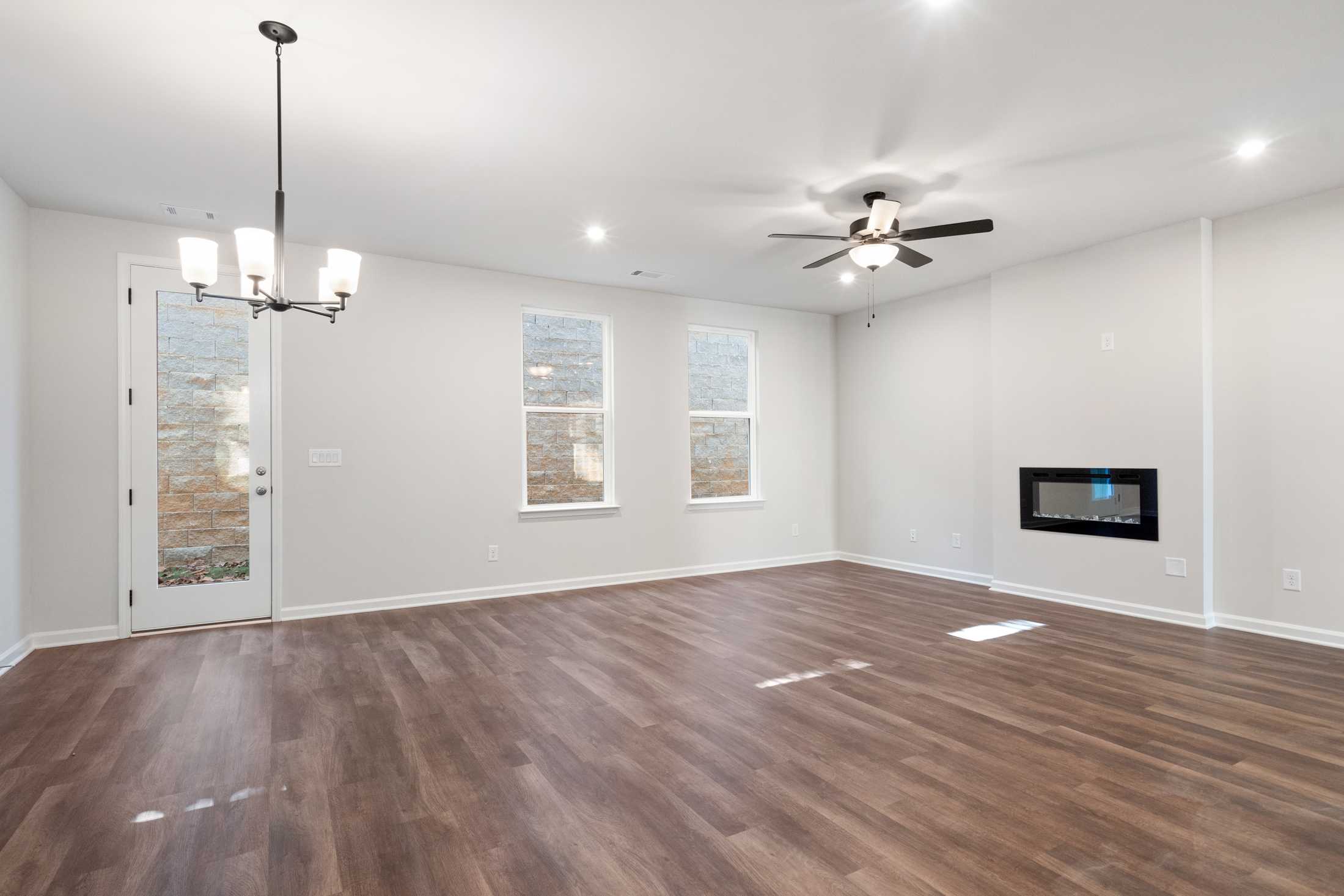 Spacious great room in The Cary B home with hardwood floors, modern linear fireplace, chandelier, and ceiling fan