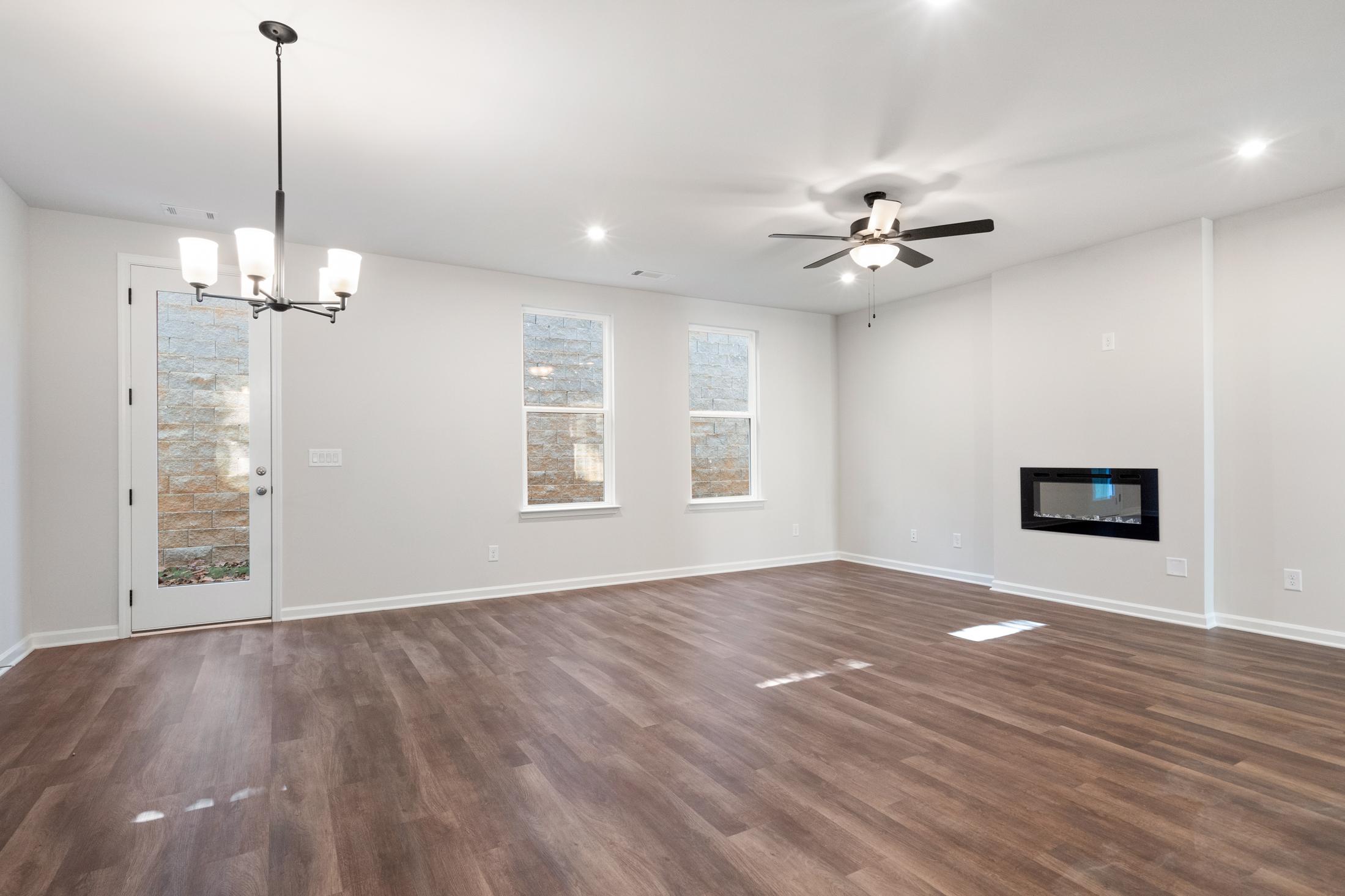 Spacious great room in The Cary B home with hardwood floors, modern linear fireplace, chandelier, and ceiling fan