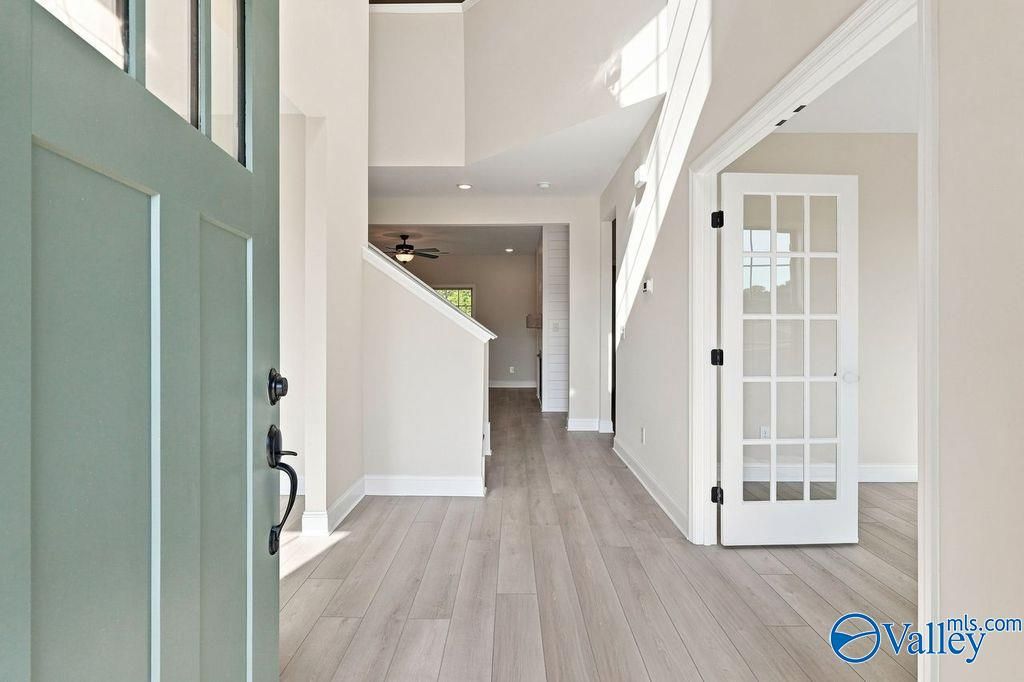 Bright foyer entry with wood-style flooring and French door office in The Madison A floor plan, Cain Park, Hartselle, AL.
