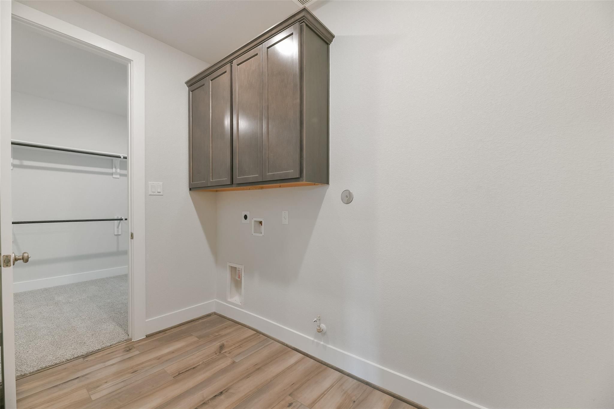 Functional laundry room with shaker cabinets, washer/dryer hookups, and open closet door in Davidson Homes The Edward A, Lago Mar, Texas City