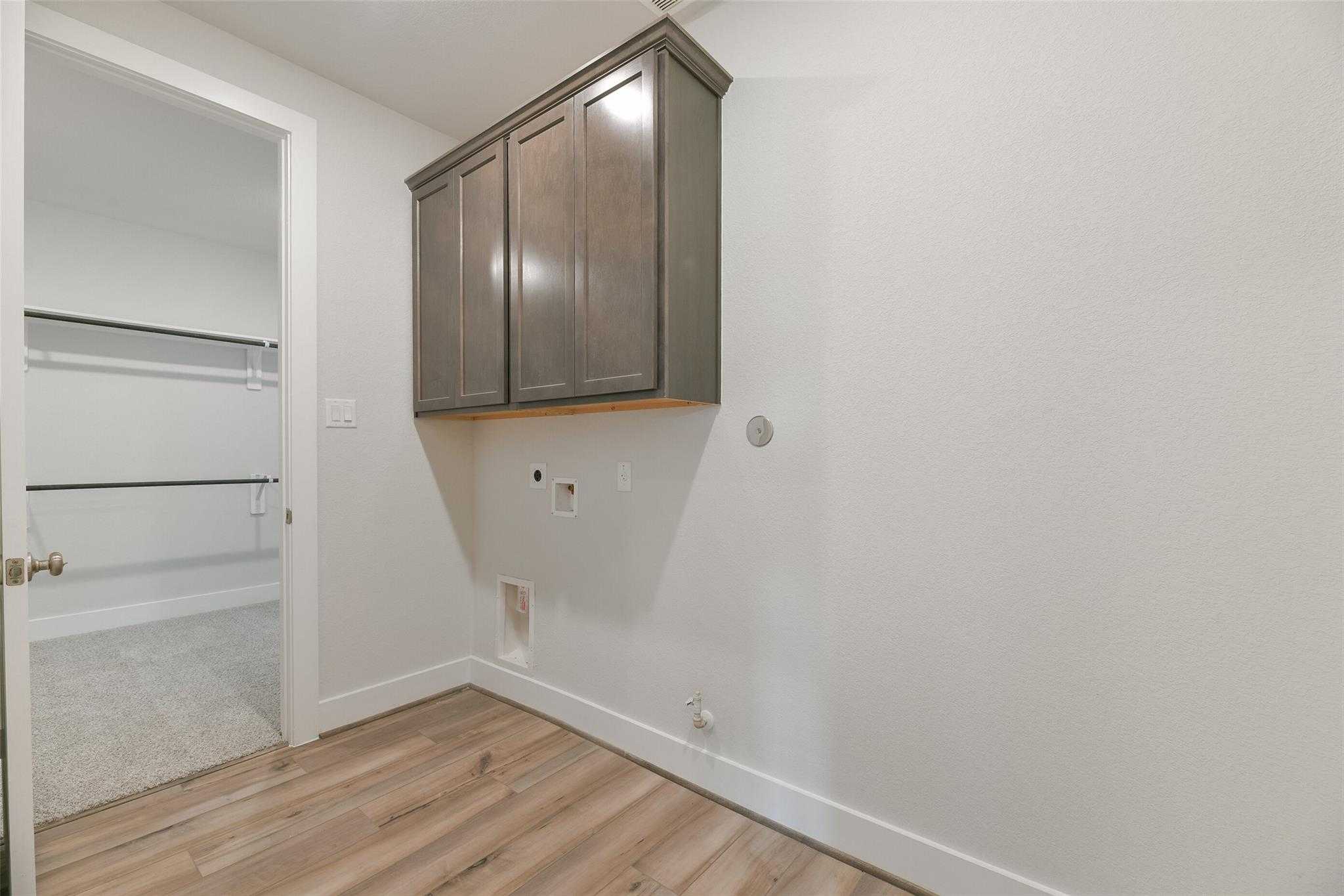 Functional laundry room with shaker cabinets, washer/dryer hookups, and open closet door in Davidson Homes The Edward A, Lago Mar, Texas City