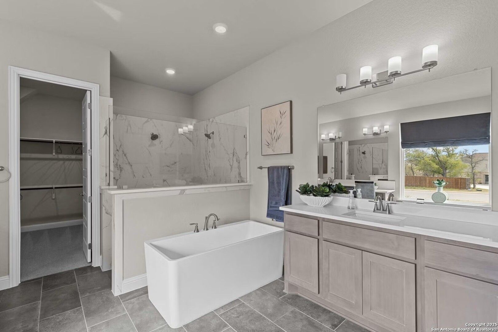 Modern master bathroom with freestanding tub, glass walk-in shower, double vanity, marble tiles in Davidson Homes The Garner B, Castroville, TX