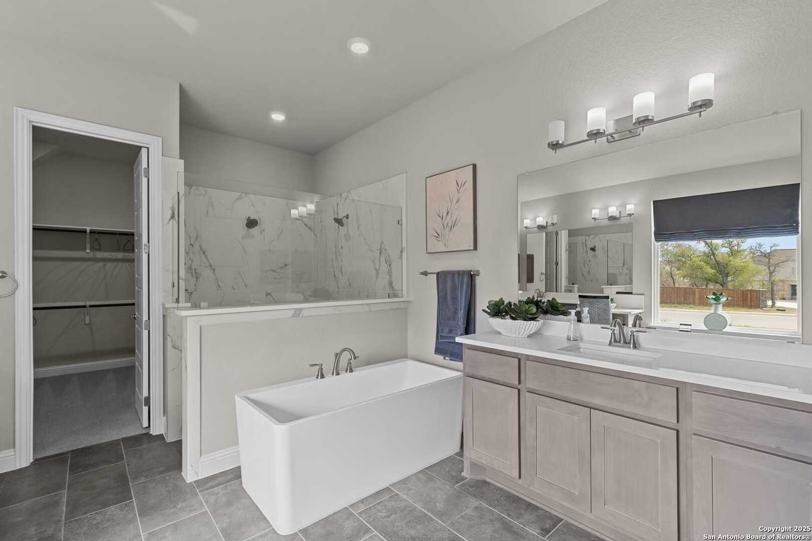 Elegant master bathroom with freestanding tub, walk-in glass shower, and double vanity in Davidson Homes The Garner A, Castroville, Texas