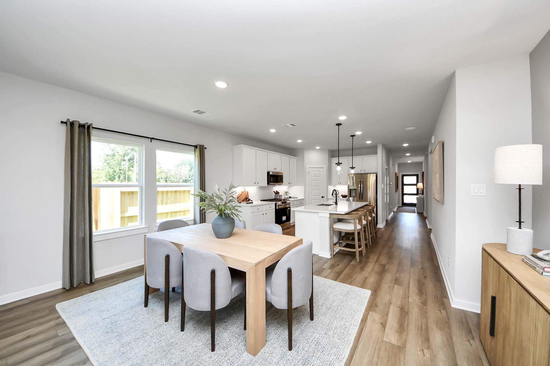 Open-concept kitchen and dining area at Enclave at Newport in Crosby, TX with modern finishes and hardwood flooring.