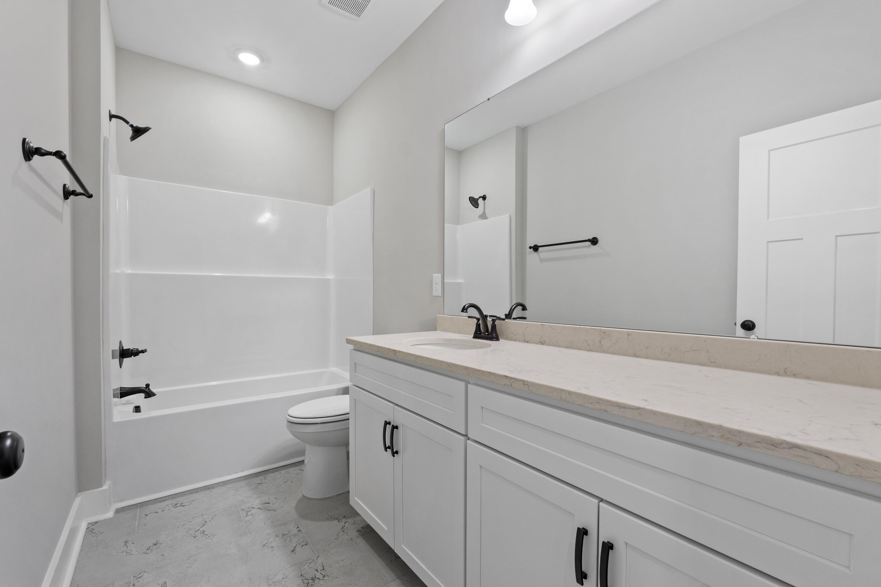 Modern master bathroom in The Oxford by Evermore Homes with white subway tile shower, soaking tub, and double vanity