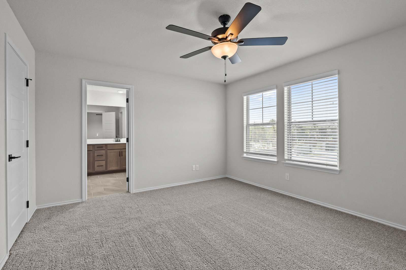 Spacious upper floor bedroom in The Florence B featuring plush carpeting, a ceiling fan, and an attached ensuite bathroom.
