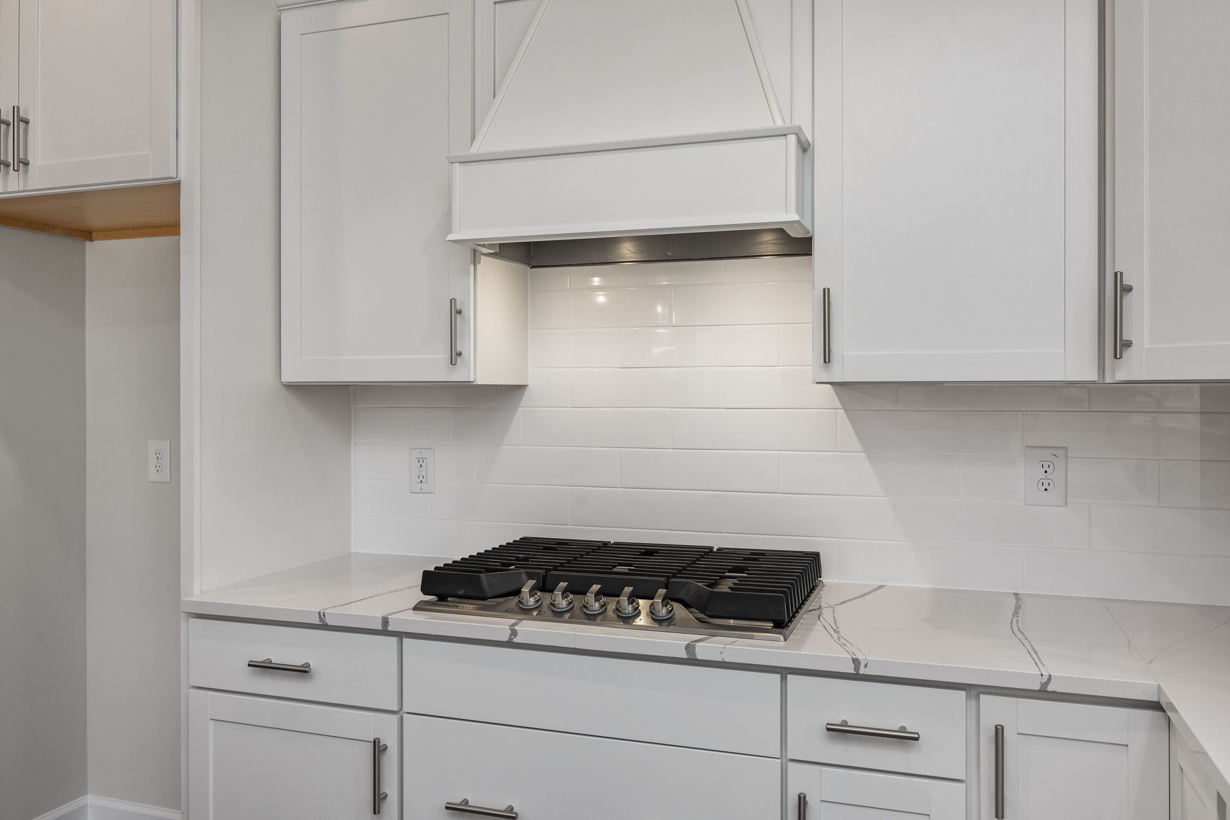 Modern kitchen in The Aspen C by Davidson Homes featuring white shaker cabinets, gas range, subway tile backsplash, and quartz counters