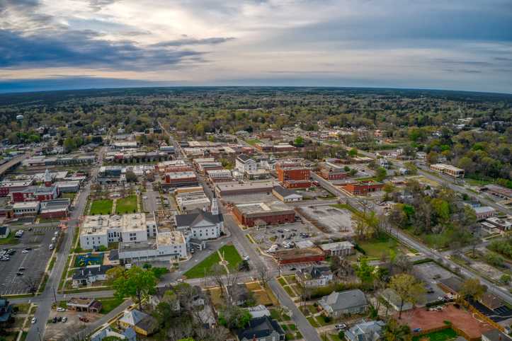 Aerial view of downtown Opelika Alabama showcasing historic brick buildings, tree-lined streets, and green spaces near Anderson Lakes community