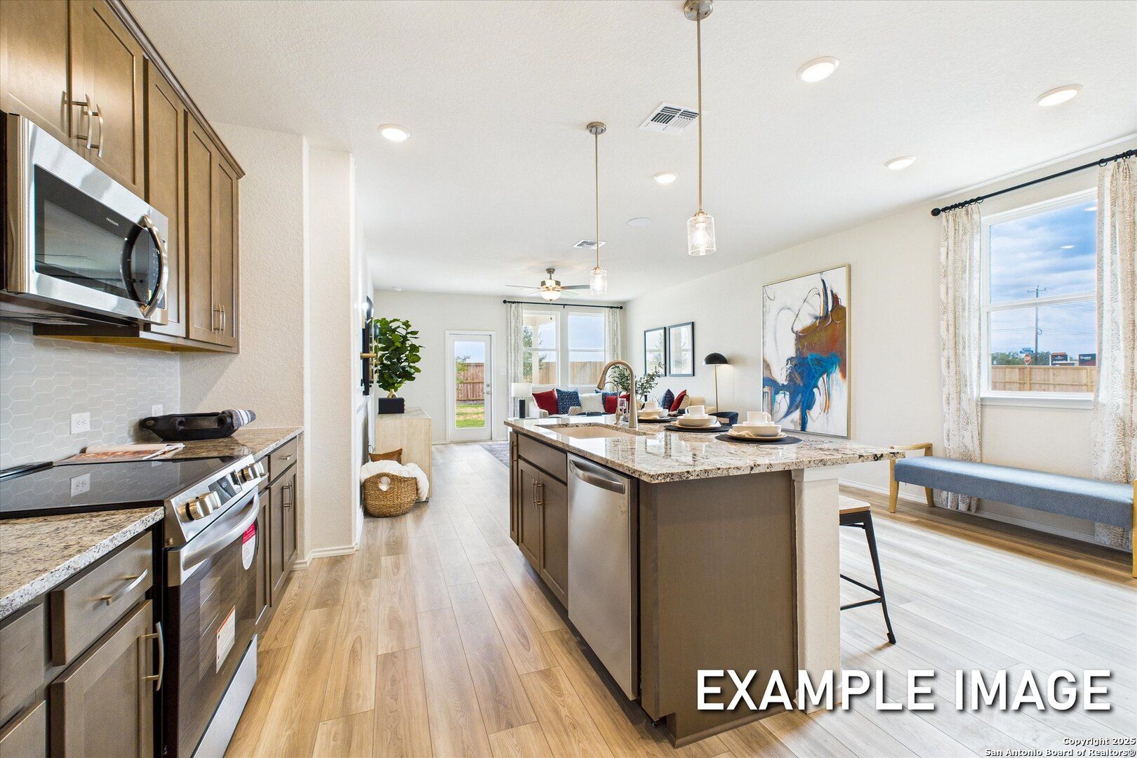 Open-concept kitchen with granite island, stainless appliances, hardwood floors in Davidson Homes The Brazos C, San Antonio, Texas