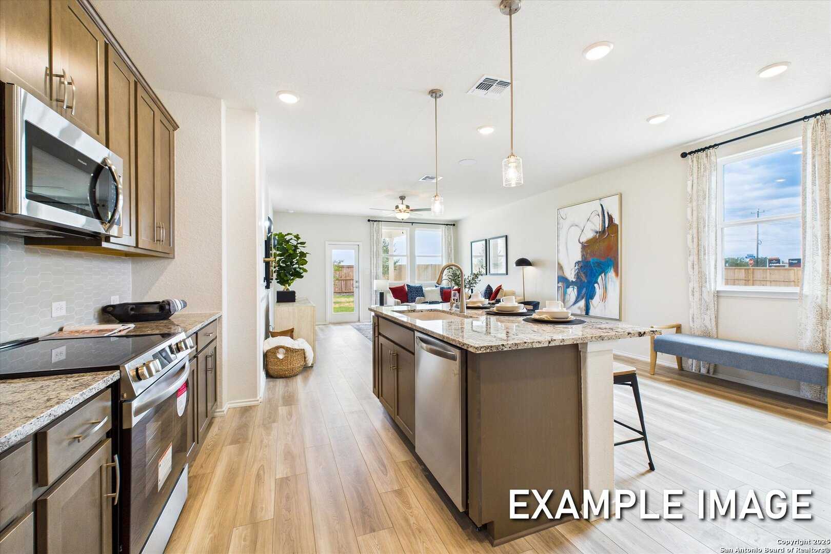 Open-concept kitchen with granite island, stainless appliances, hardwood floors in Davidson Homes The Brazos C, San Antonio, Texas