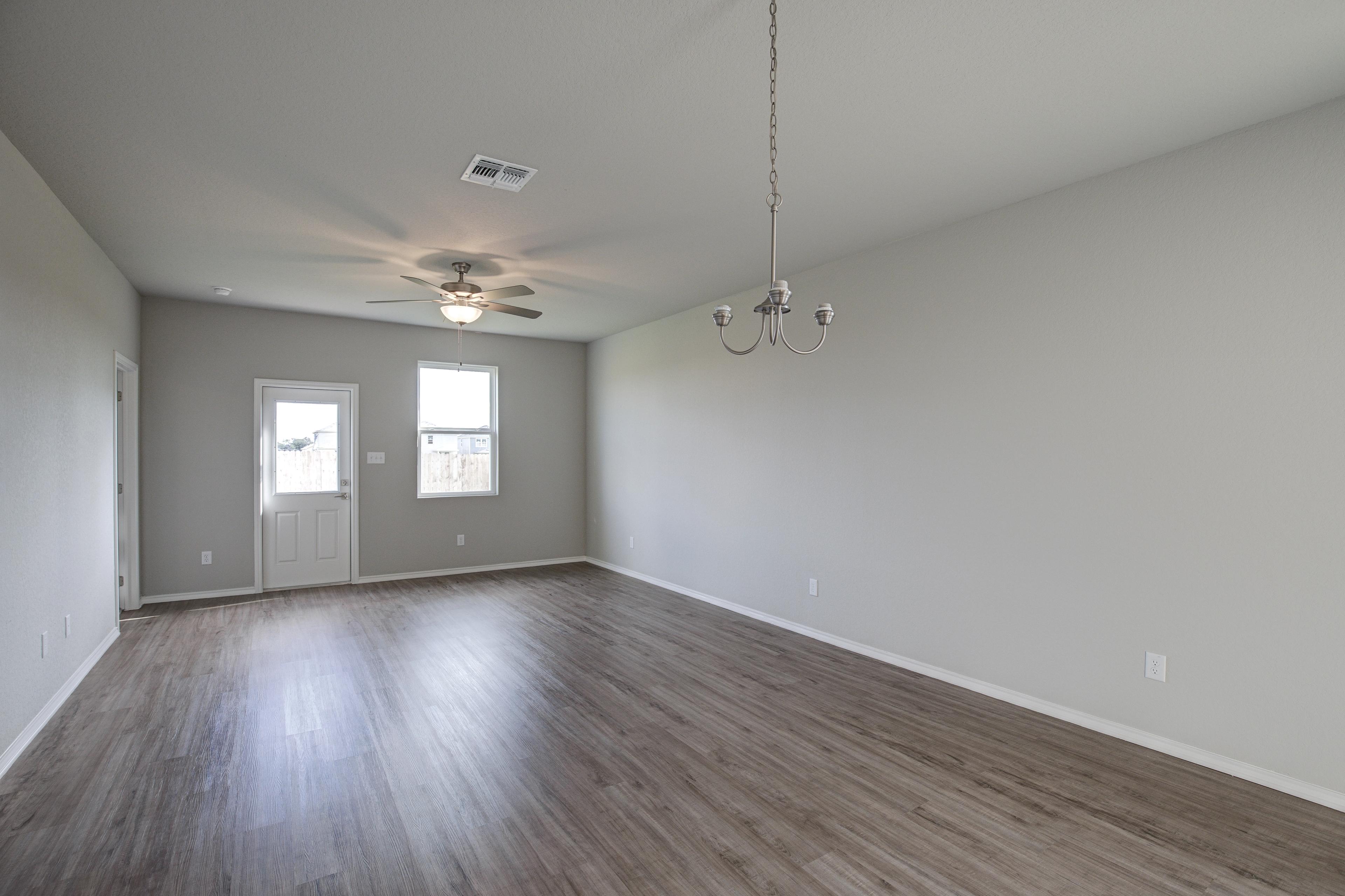 Spacious open living area in The Frio D home with gray walls, hardwood floors, ceiling fan, and chandelier