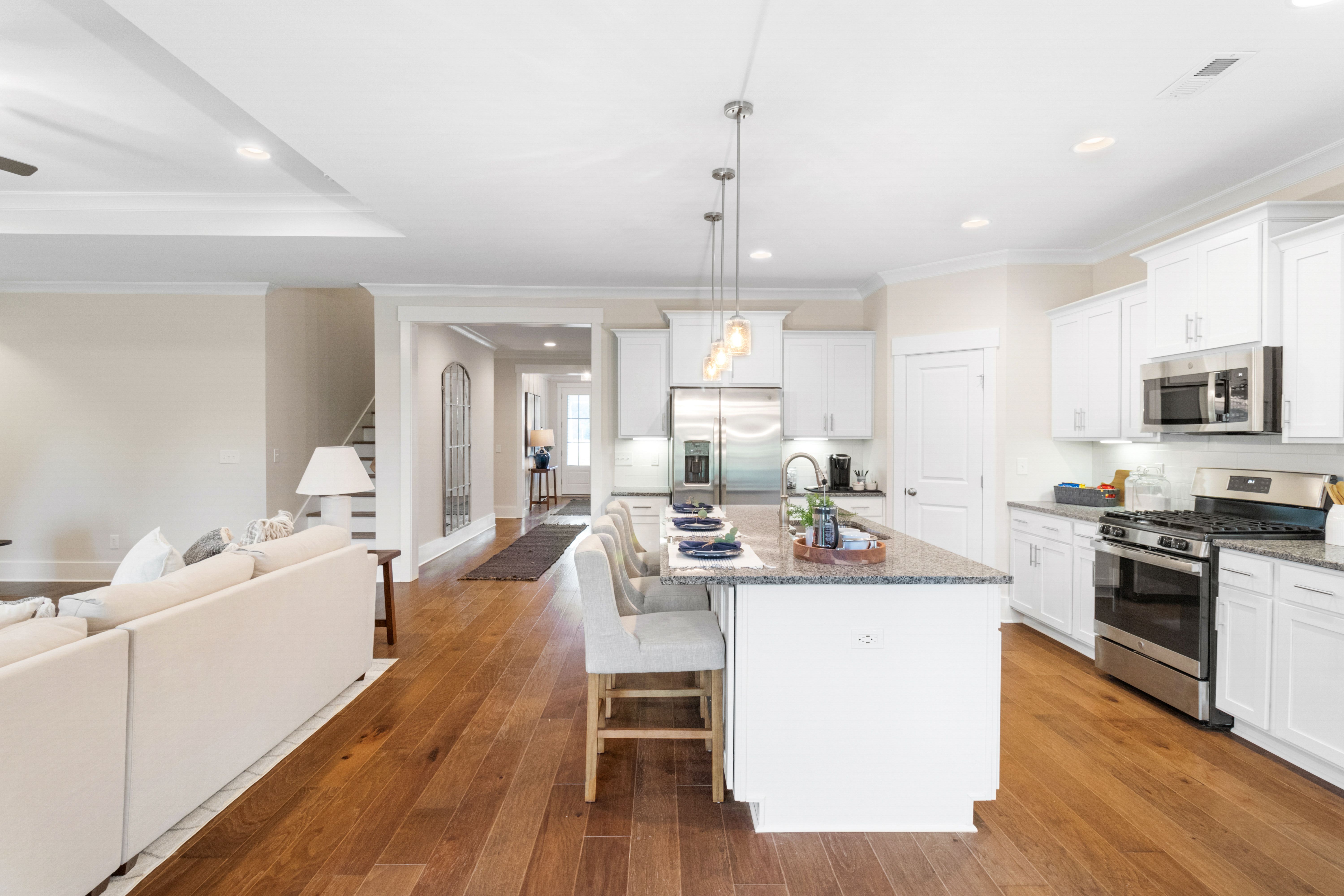 Open-concept kitchen and living room in Noble Ridge Cullman Alabama with white cabinets, granite island, hardwood floors