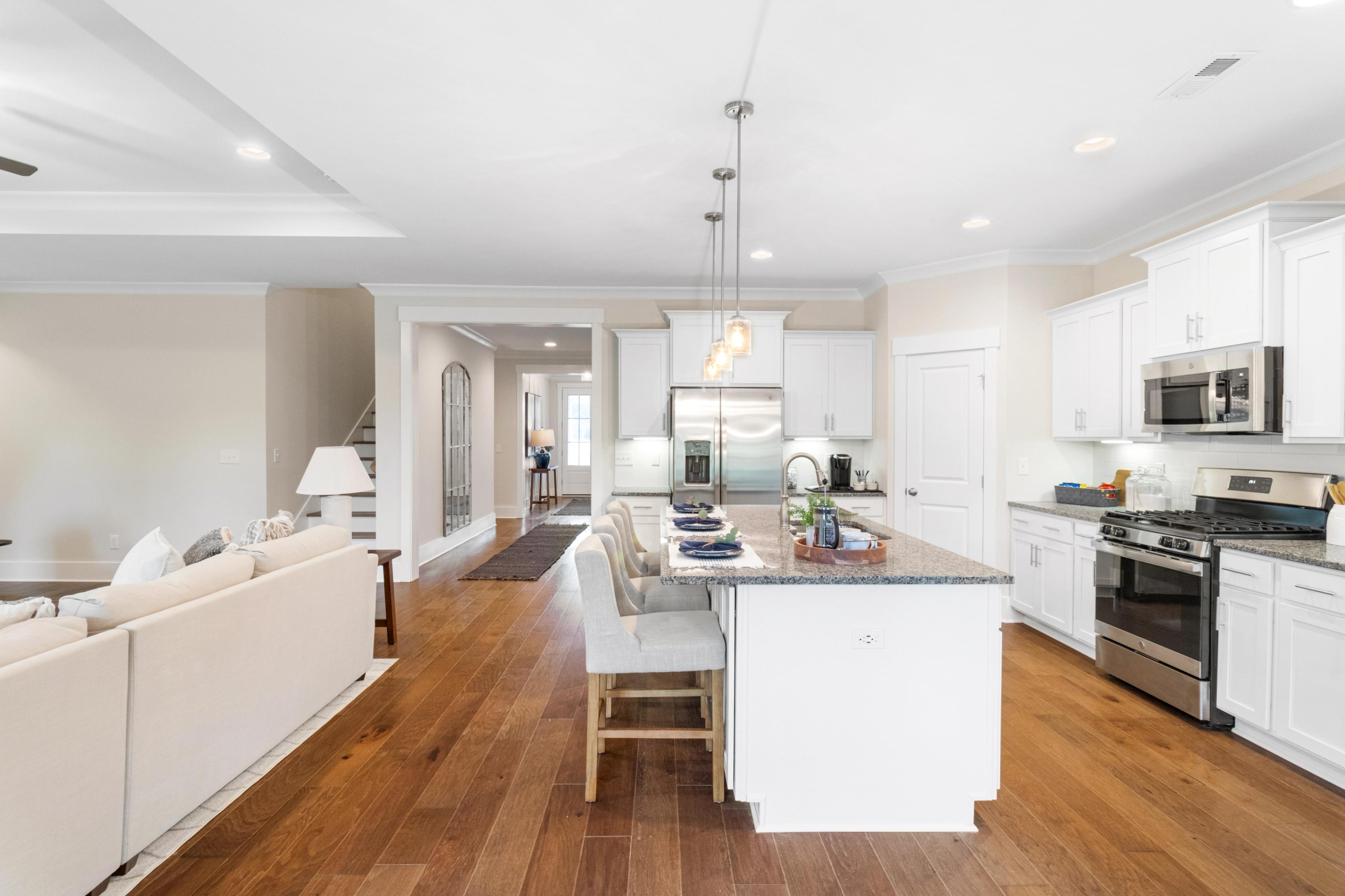 Open-concept kitchen and living room in Noble Ridge Cullman Alabama with white cabinets, granite island, hardwood floors
