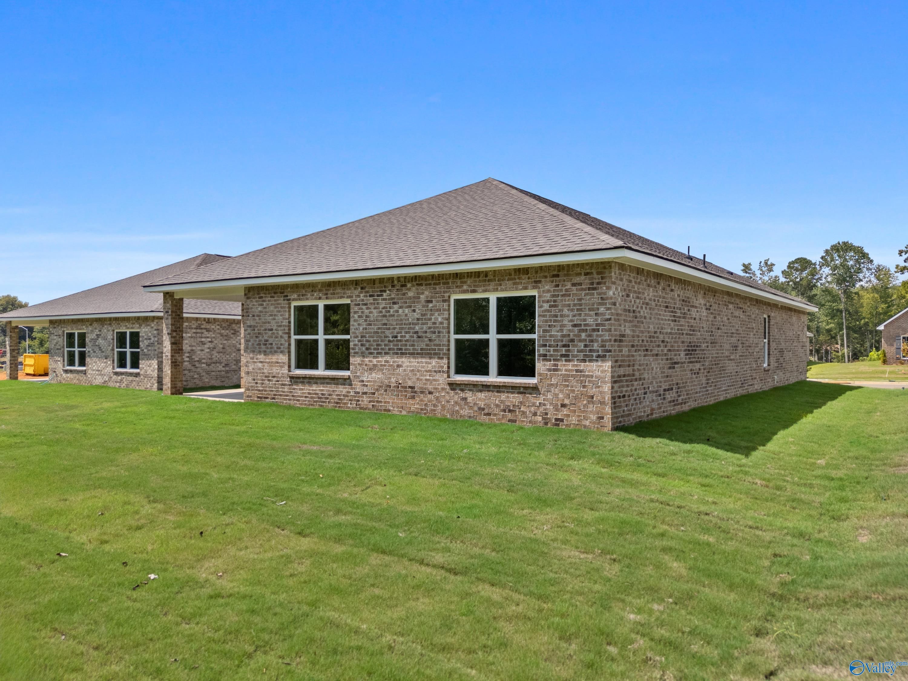 Single-story brick home with two-car garage and large windows, lush green lawn, blue sky in Spragins Cove, Huntsville, AL by Davidson Homes