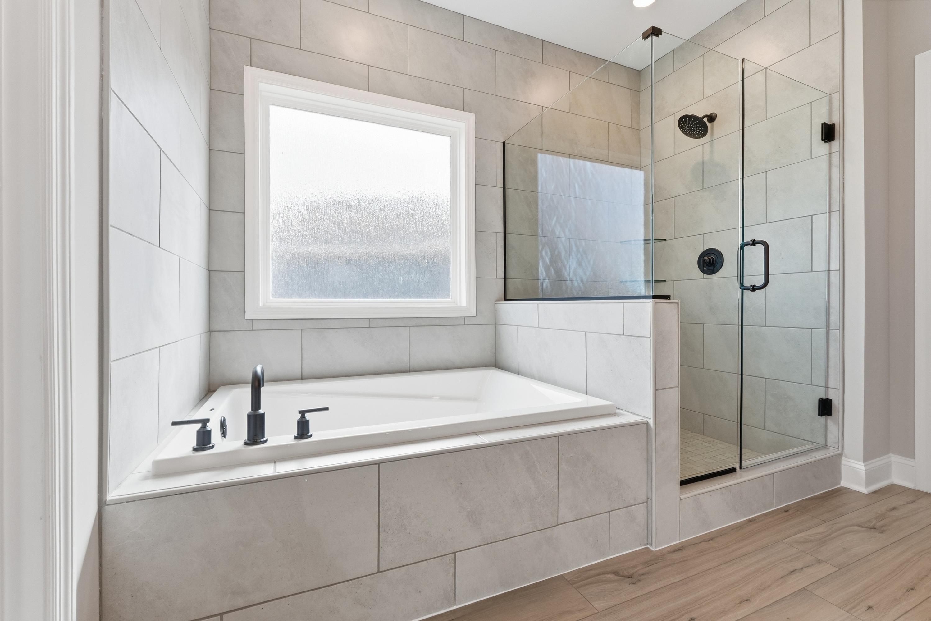 Modern master bathroom in The Rockford home design featuring white subway tile, freestanding tub, and glass shower