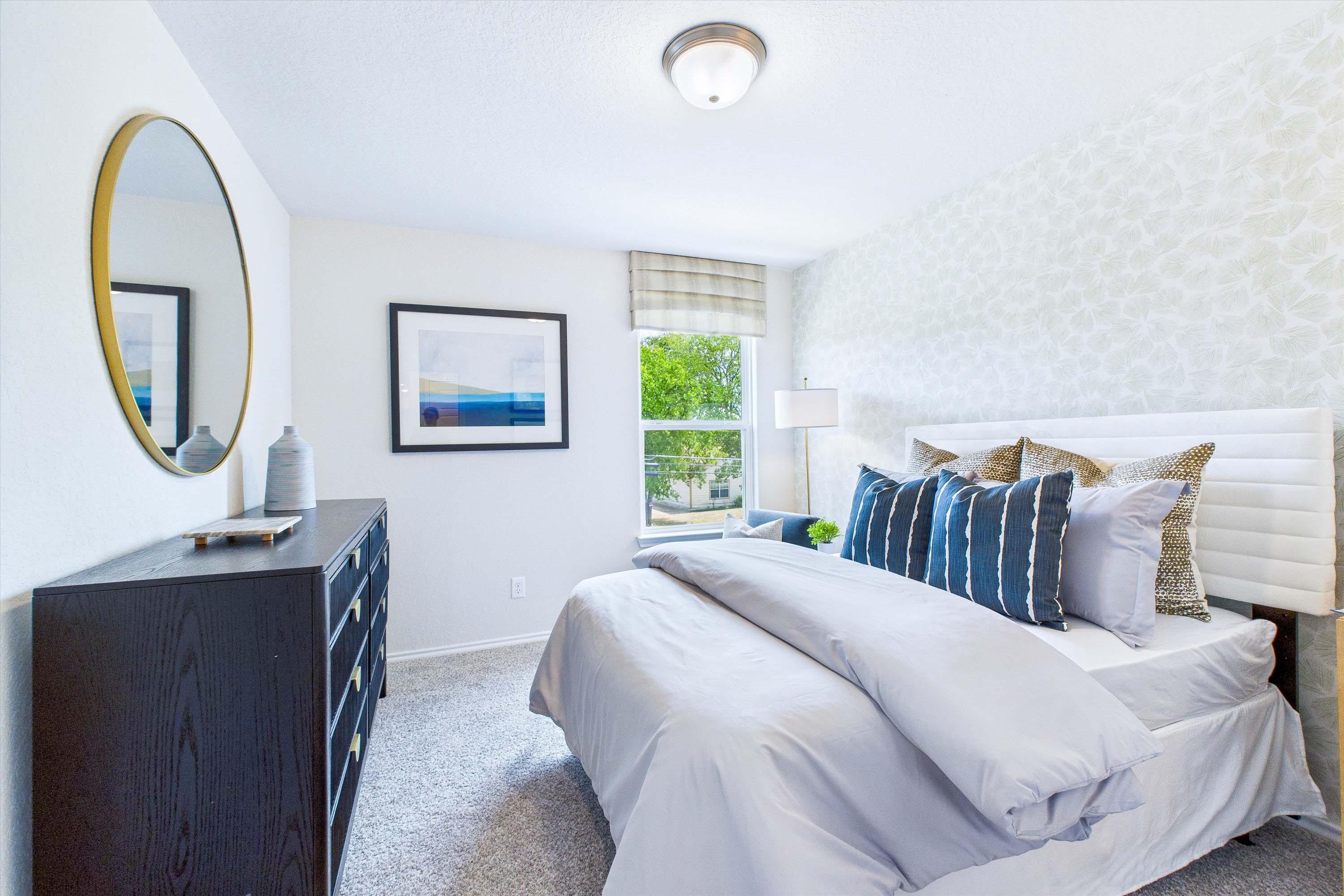 Bright secondary bedroom in The Gillian C by Davidson Homes, featuring a modern bed, patterned wallpaper, and dresser.