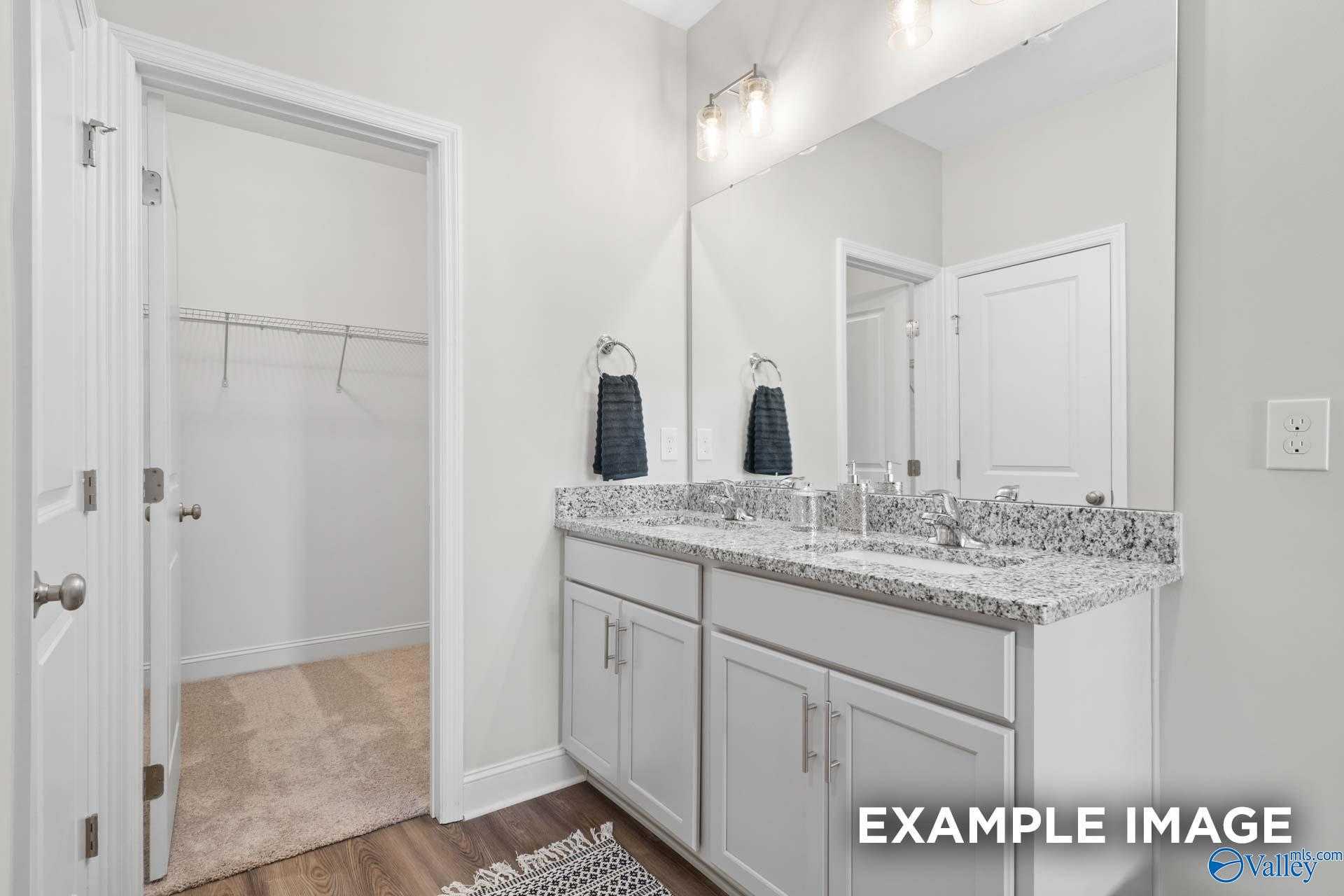 Modern master bathroom featuring double granite vanity, mirrors, and open walk-in closet in Davidson Homes The Franklin C, Meridianville