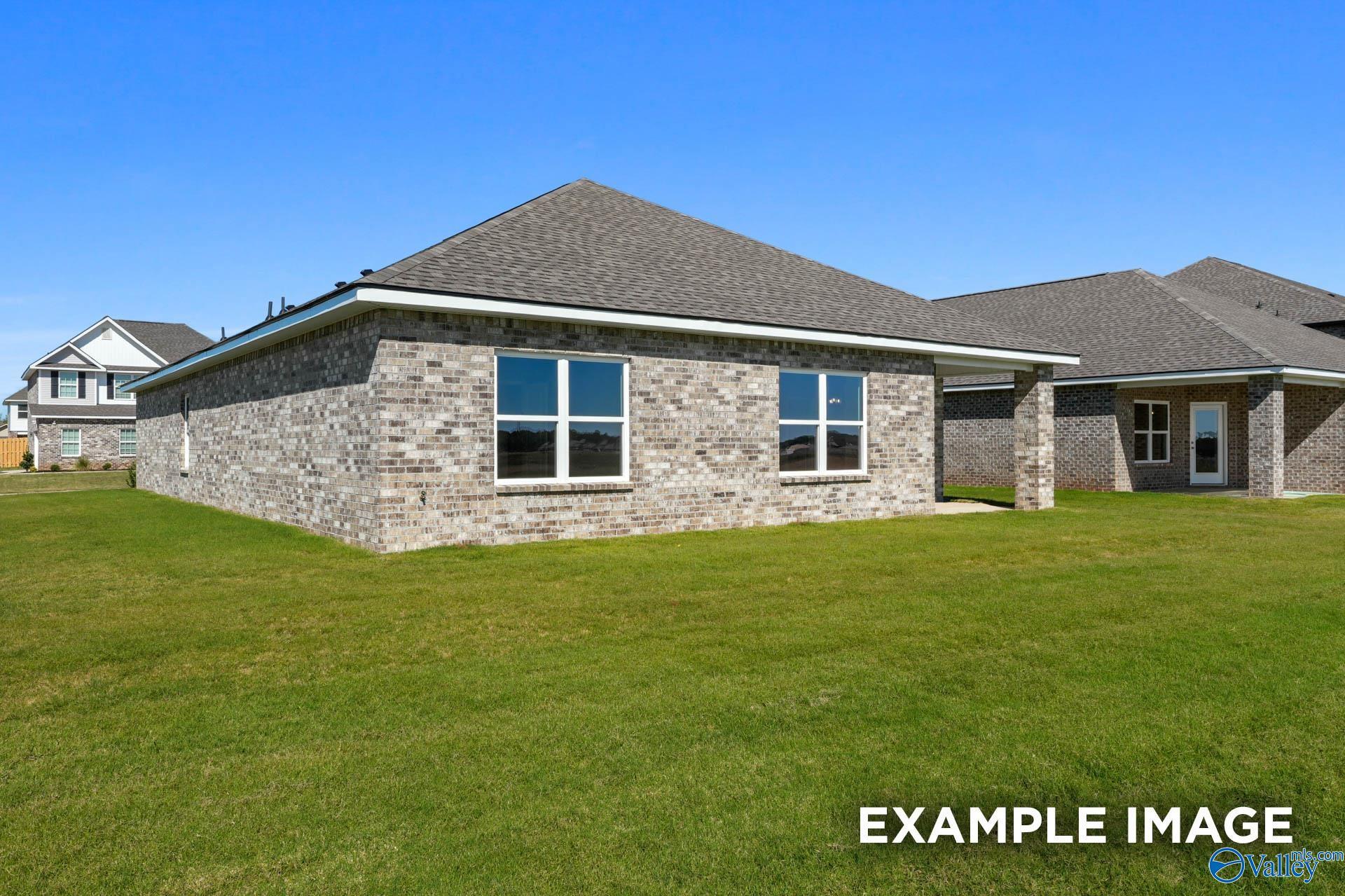 Single-story brick home with gabled roof, double windows, and 2-car garage on lush green lawn in Ricketts Farm, Athens, Alabama