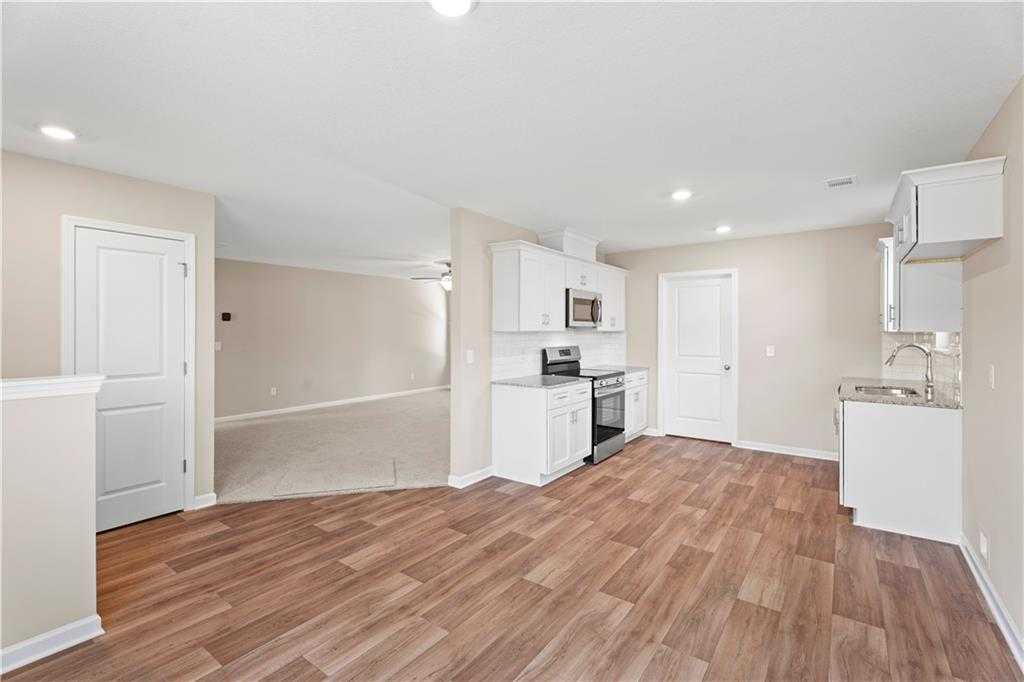 Open-concept kitchen featuring white cabinets, stainless appliances, and hardwood floors in Davidson Homes The Washington, Phenix City, Alabama