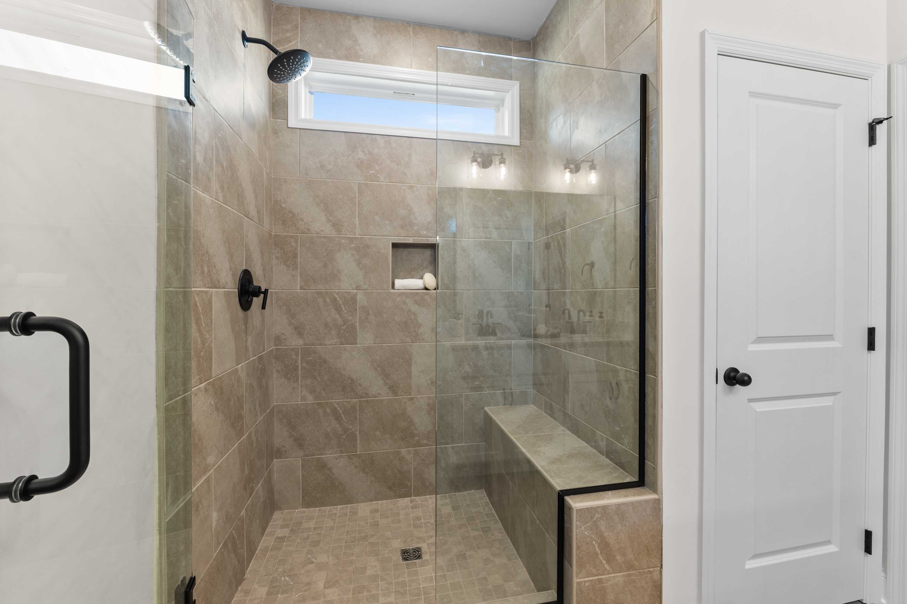 Spacious tiled walk-in shower in Lynn Meadows home, Meridianville Alabama with glass enclosure, bench seat and rainfall showerhead