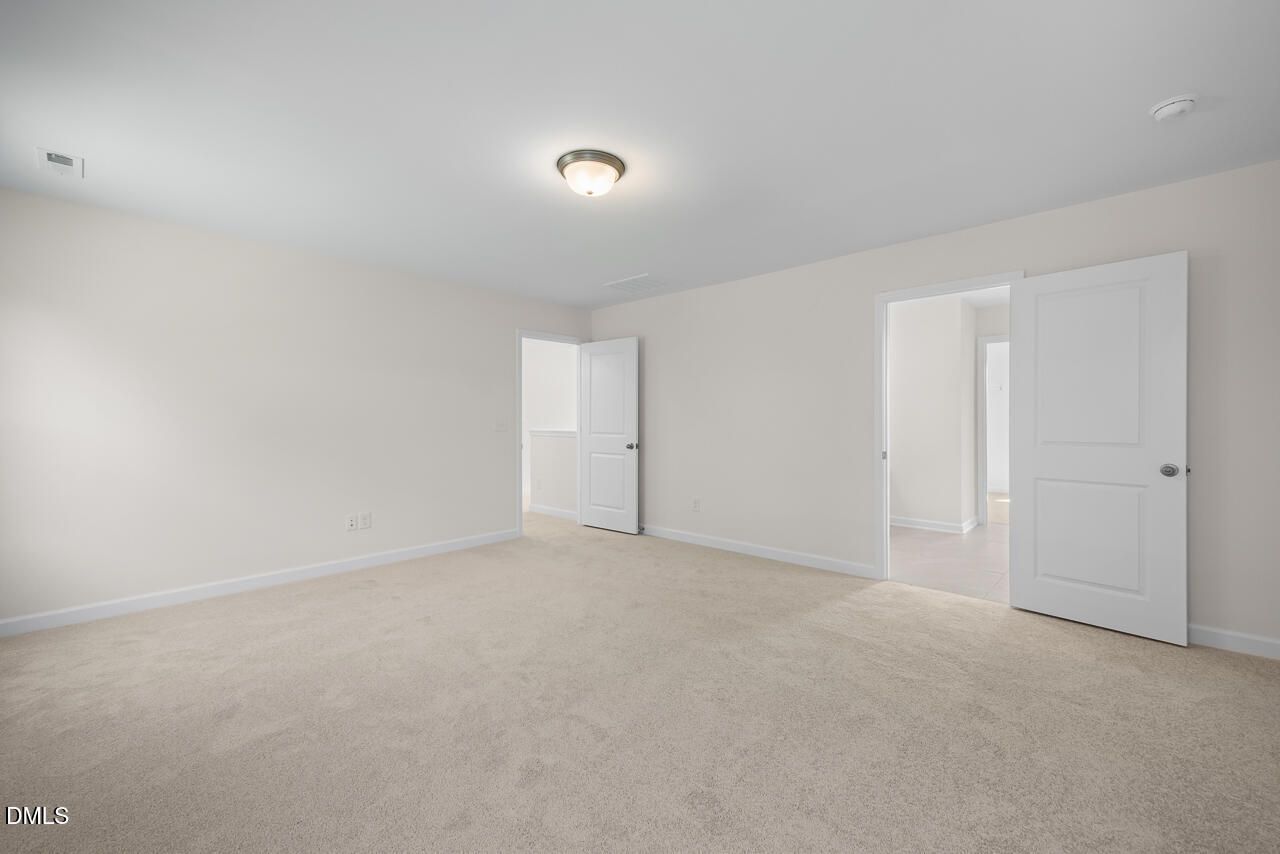 Spacious carpeted bedroom with white doors in Davidson Homes The Willow B, new construction home in Woodland Crossing, Zebulon NC