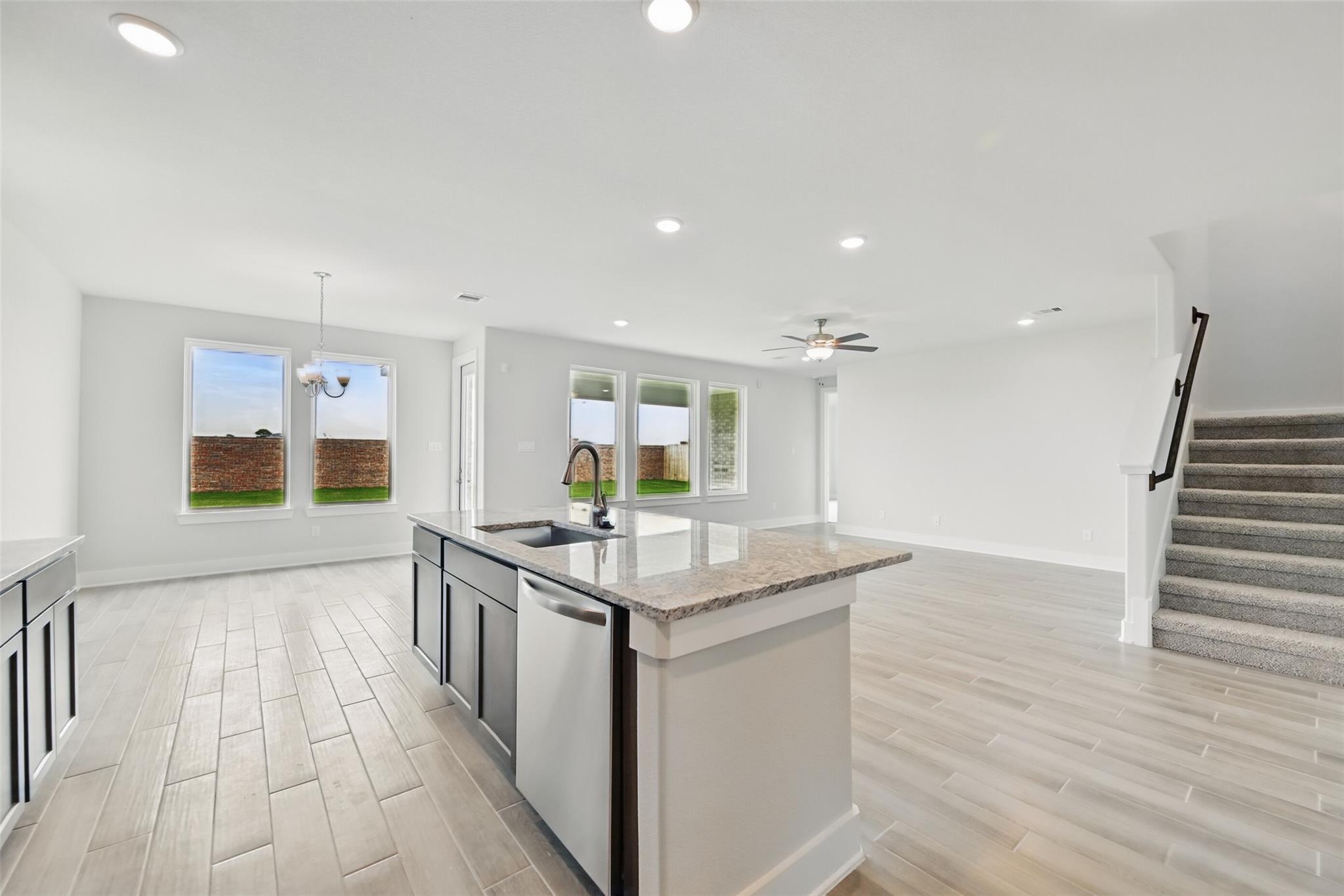Open-concept kitchen with granite island, stainless dishwasher, and large windows to backyard in Davidson Homes The Philip A, Texas City