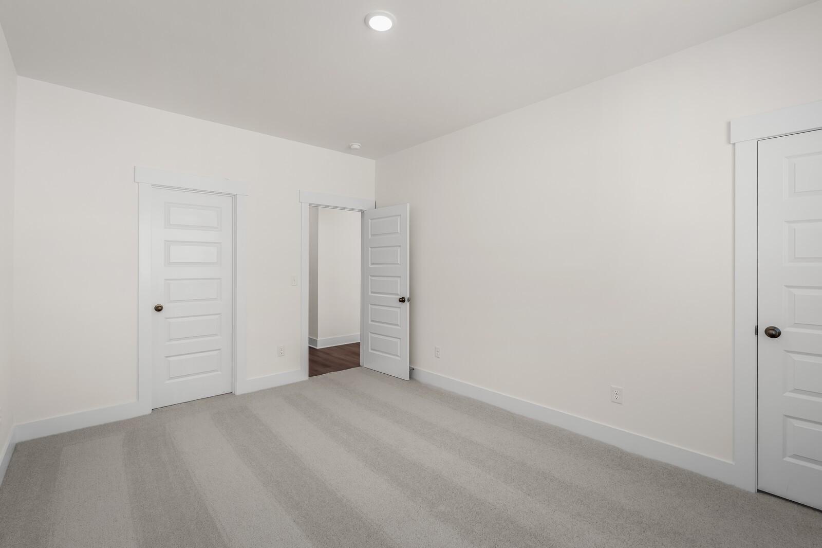 Spacious bedroom with plush carpet and white paneled doors in The Willow floor plan at Woods Crossing, Gallatin, Tennessee.
