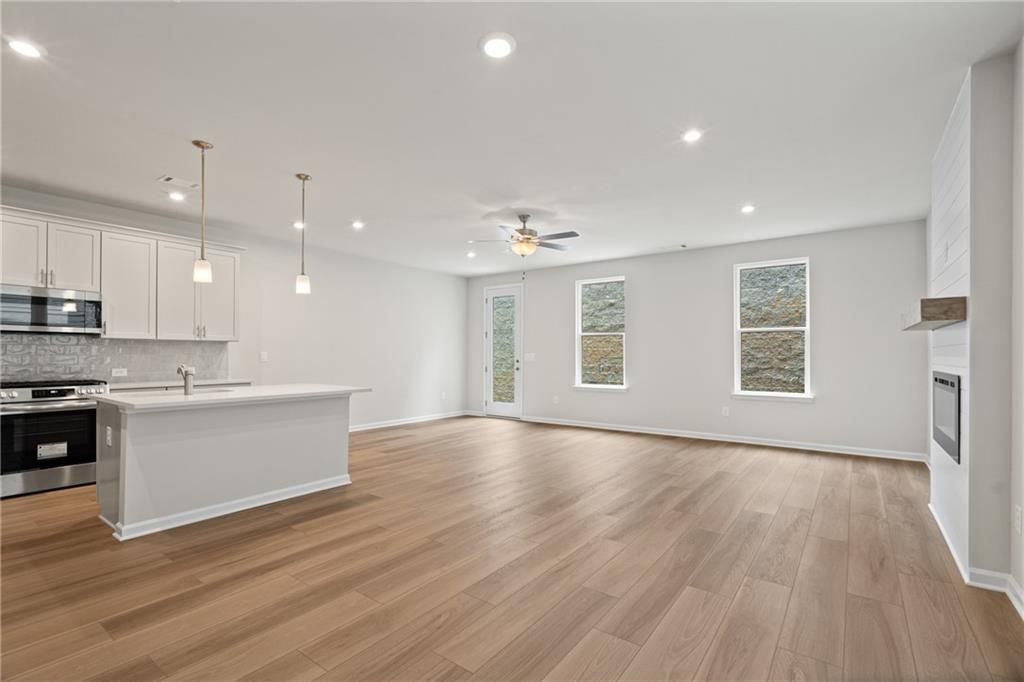 Open-concept kitchen-living area with white island, stainless appliances, fireplace, and large windows in Davidson Homes The Marion B, Kennesaw, GA