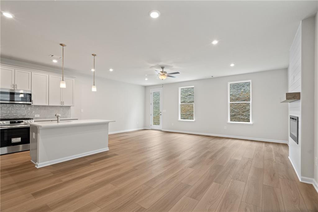 Open-concept kitchen-living area with white island, stainless appliances, fireplace, and large windows in Davidson Homes The Marion B, Kennesaw, GA