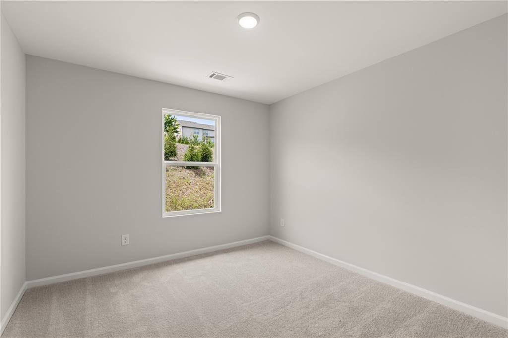 Bright bedroom with neutral carpet in The Hartwell A floor plan by Davidson Homes at The Bluffs in Canton, Georgia.