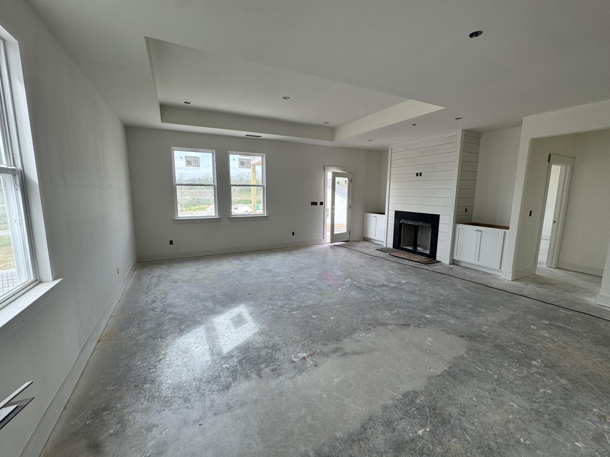 Spacious living room with stone fireplace, large windows, and open layout in unfinished Davidson Homes The Cottonwood E, Gallatin, TN