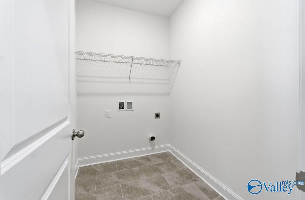 Bright white laundry room with wire shelving, washer/dryer hookups, and tiled floor in Davidson Homes The Montgomery, Hartselle, AL