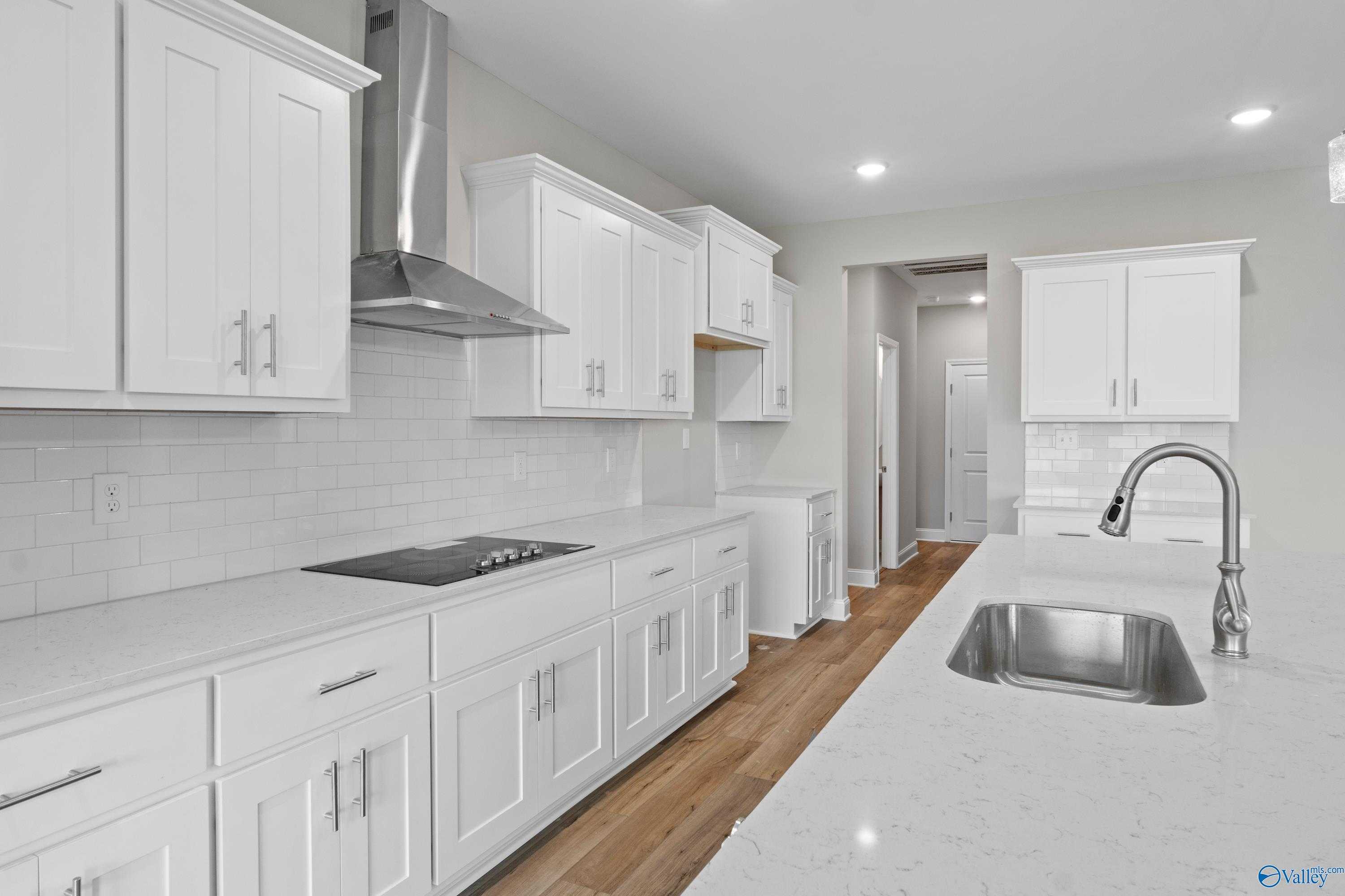 Modern white kitchen with quartz island, stainless range, subway tile backsplash in Davidson Homes The Finleigh, Meridianville AL