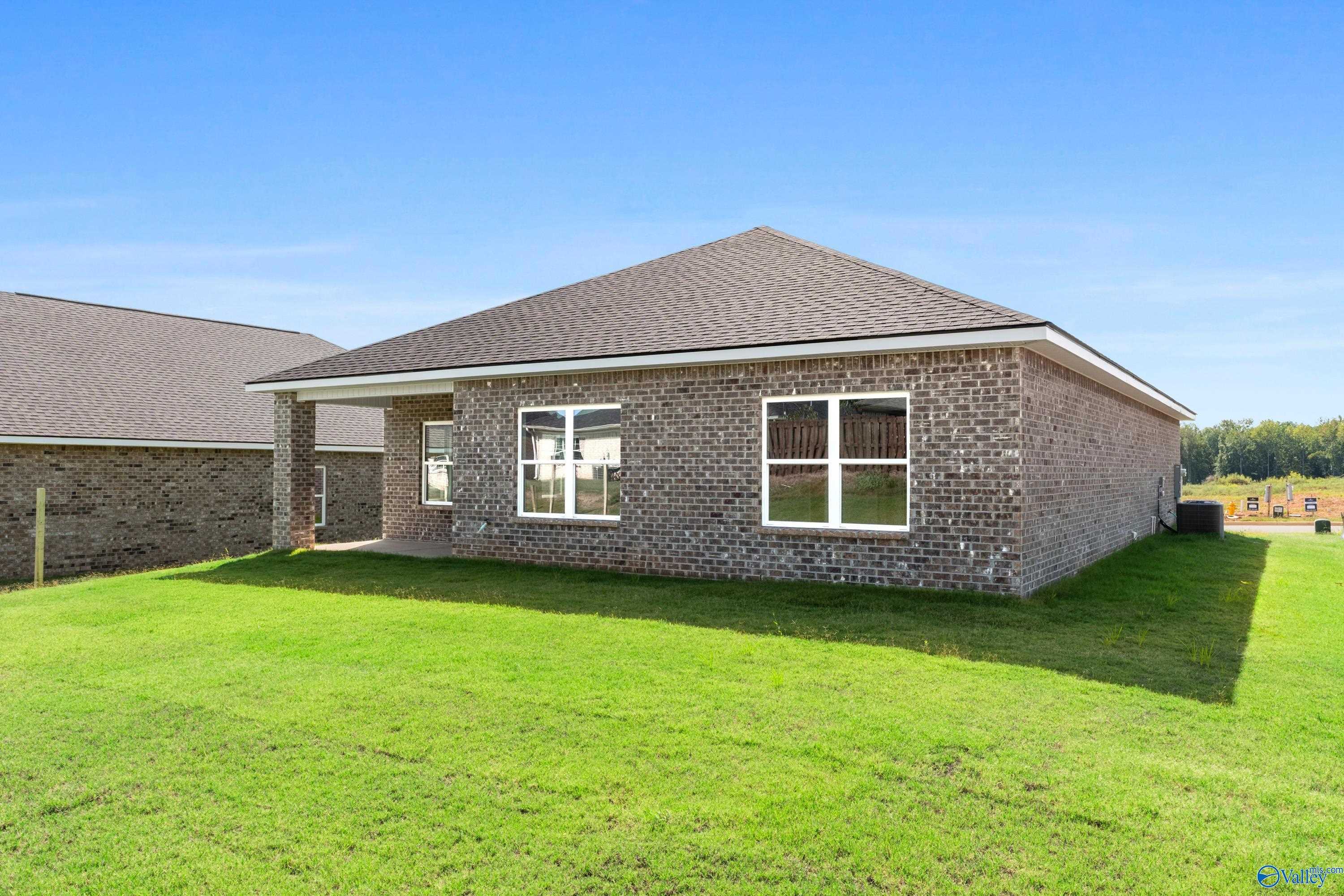Single-story brick ranch home with gabled roof, covered porch, and large windows on green lawn in Wood Trail, Toney, Alabama