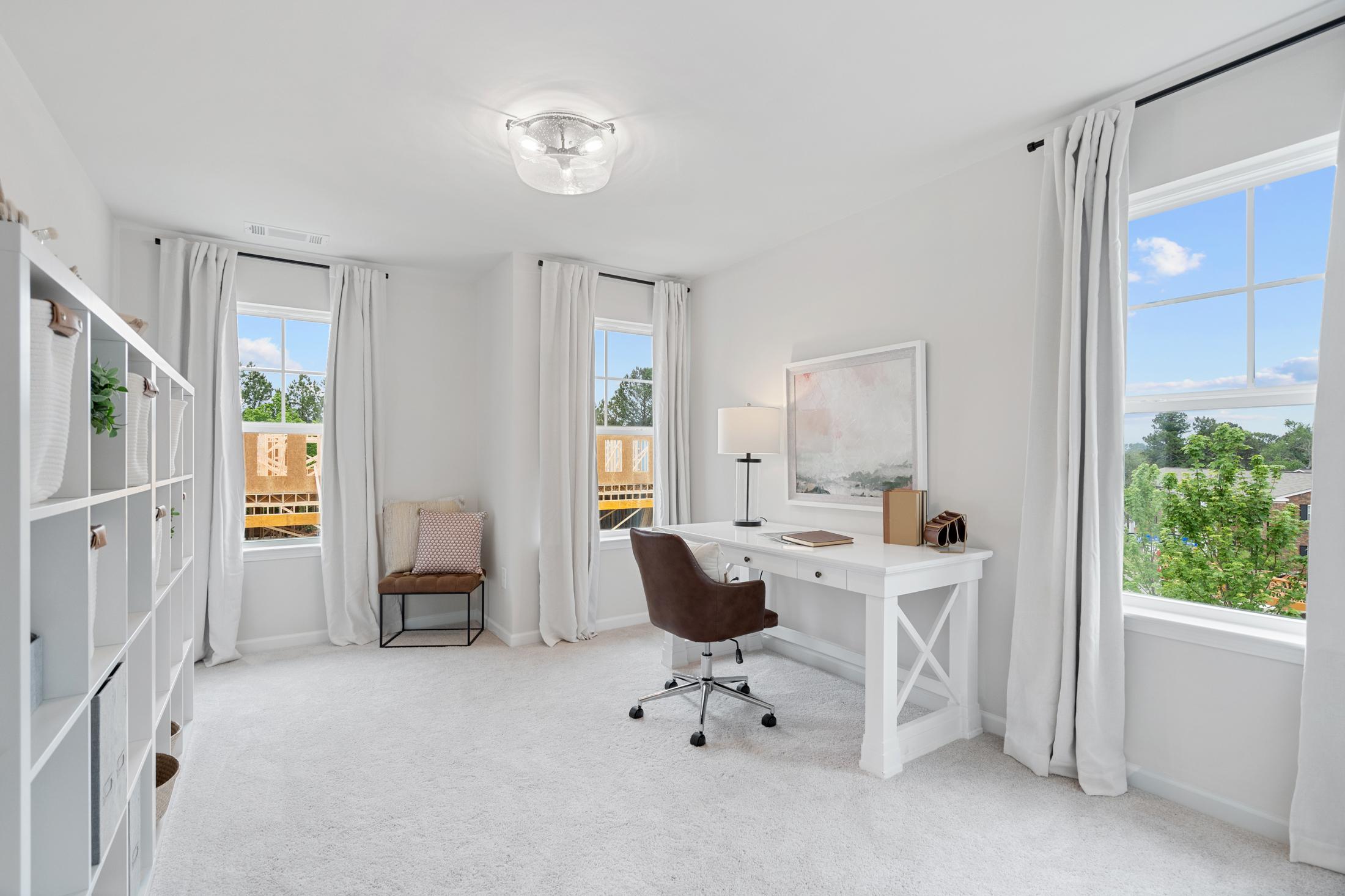 Spacious home office at Rosehill Townhomes in Marietta GA with white walls, large windows, wooden desk, and bookshelves