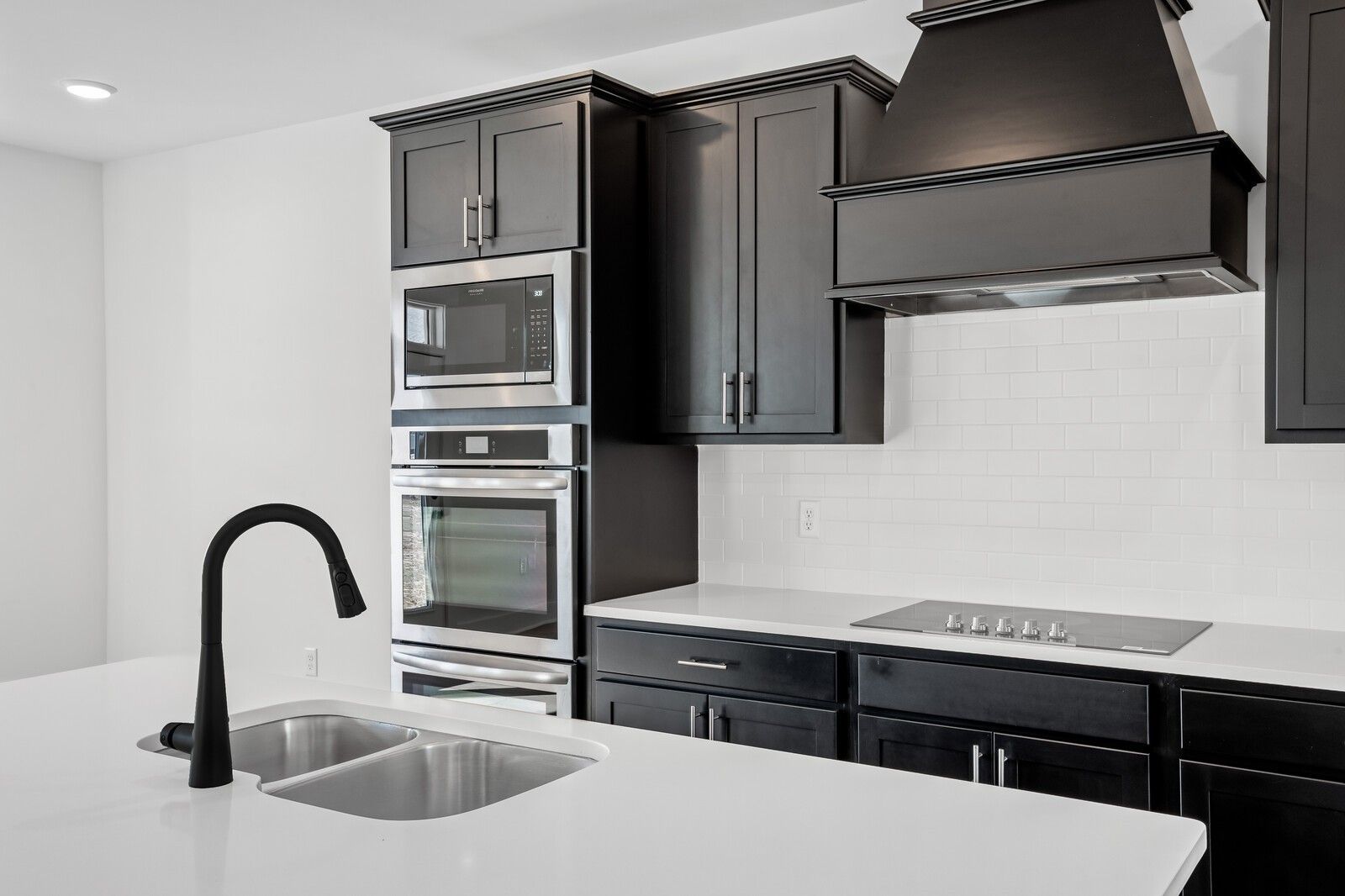 Modern kitchen with black shaker cabinets, white quartz island, stainless double ovens in Davidson Homes The Willow C, Gallatin TN