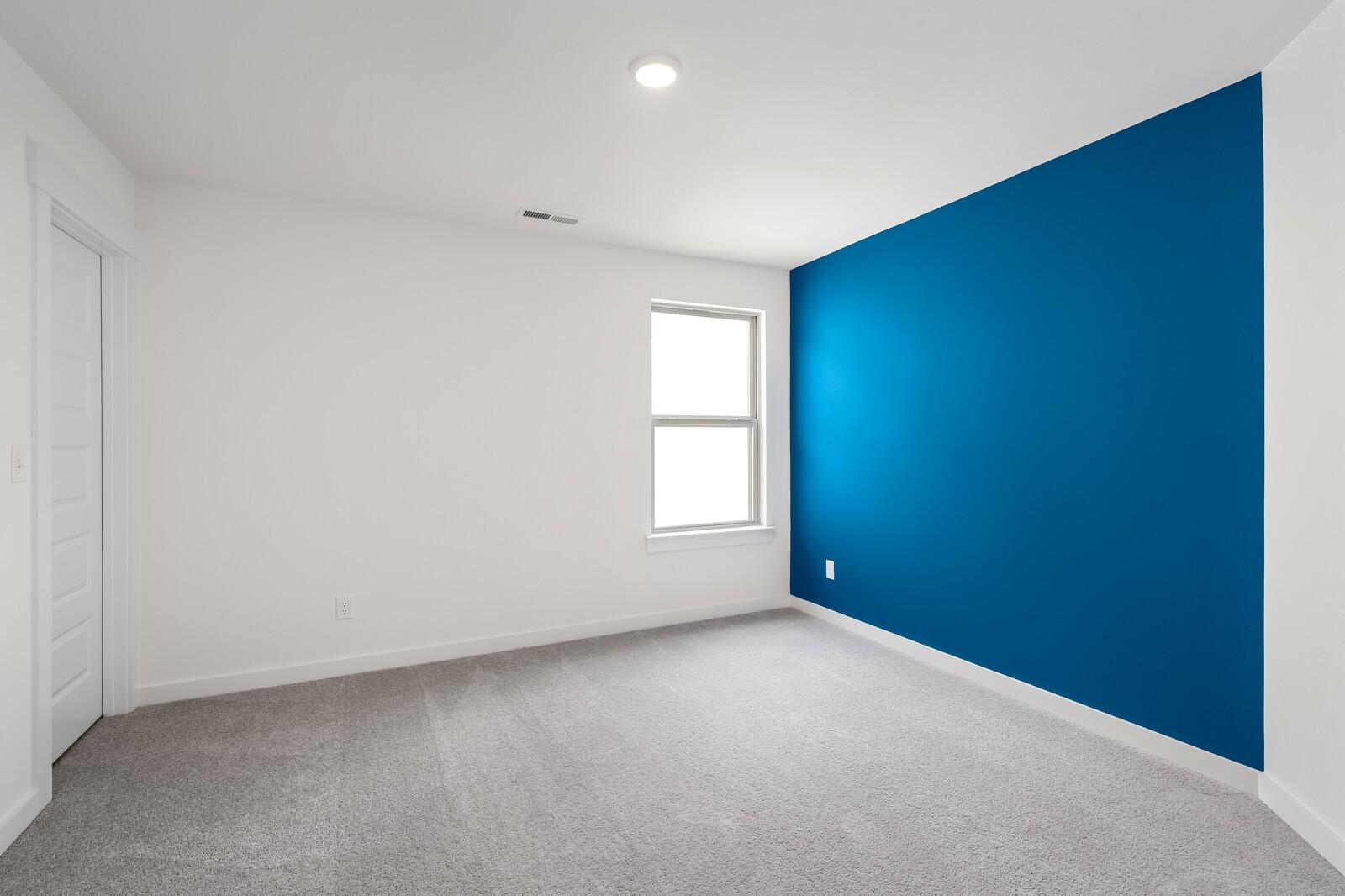 Bright bedroom with blue accent wall and carpet in The Ridgeport C floor plan at Woods Crossing, Gallatin, Tennessee.