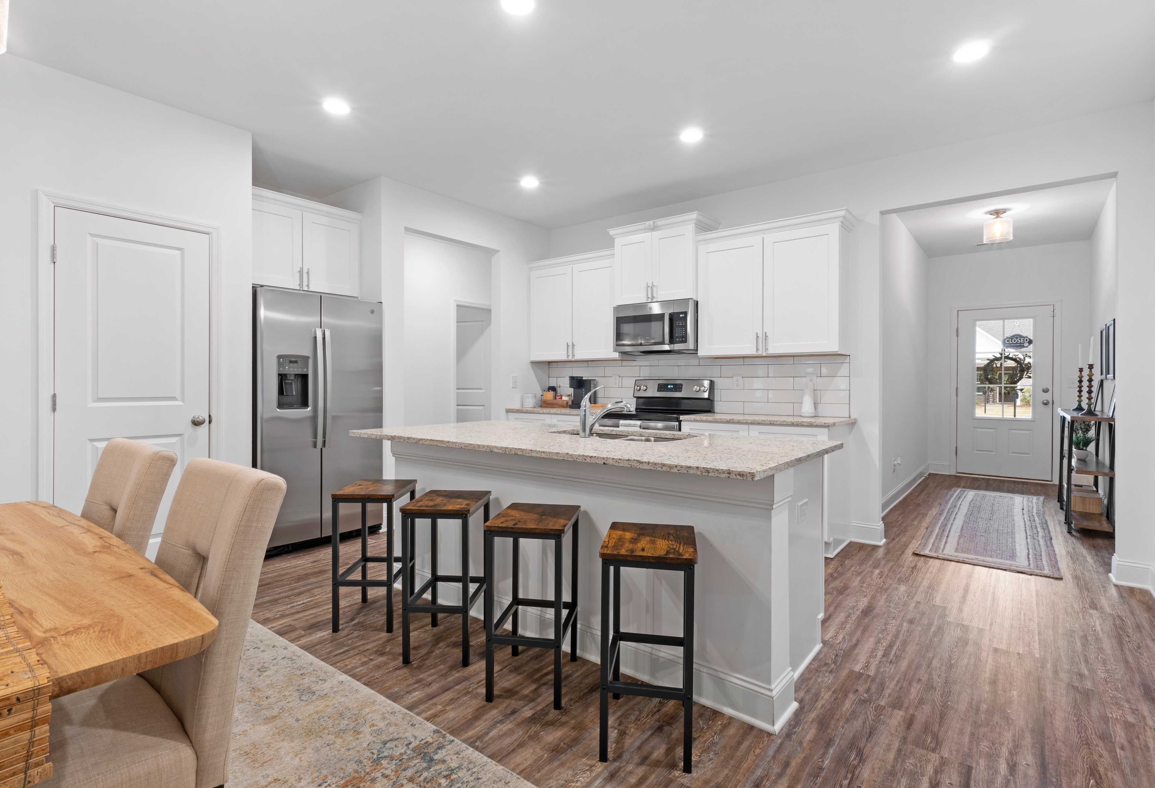 Spacious open-concept kitchen and dining in The Cumberland with white cabinets, large island, stainless steel appliances