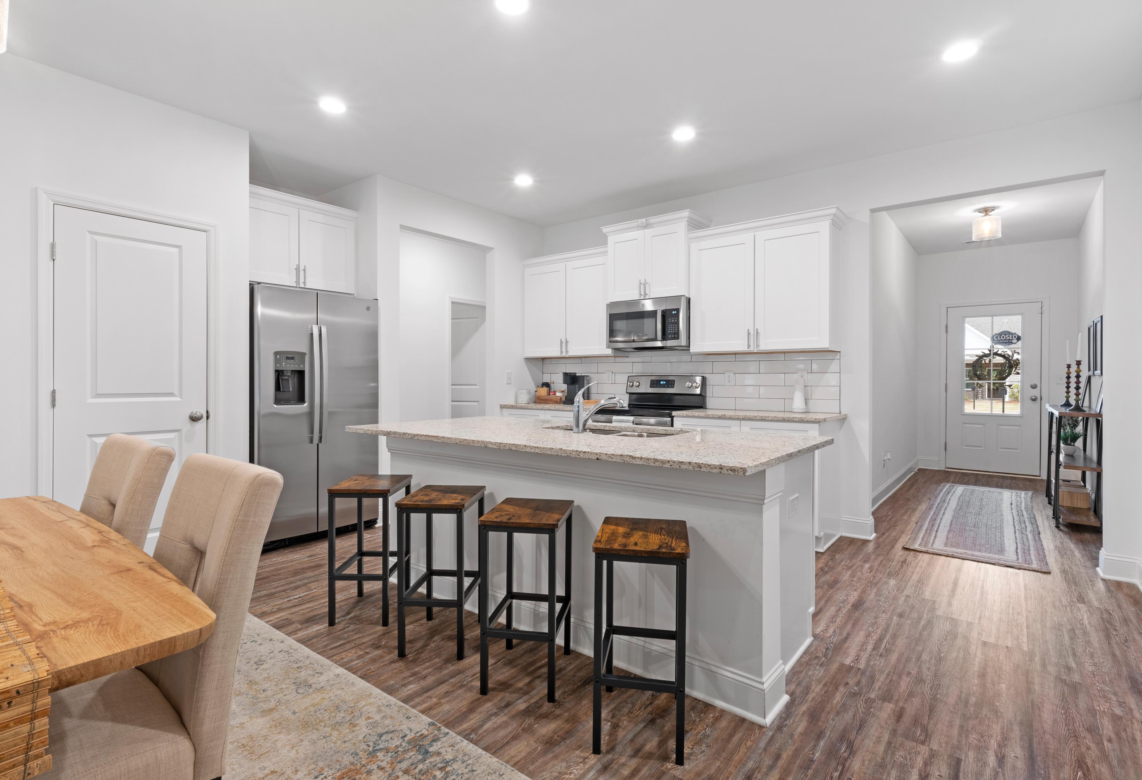 Spacious open-concept kitchen and dining in The Cumberland with white cabinets, large island, stainless steel appliances