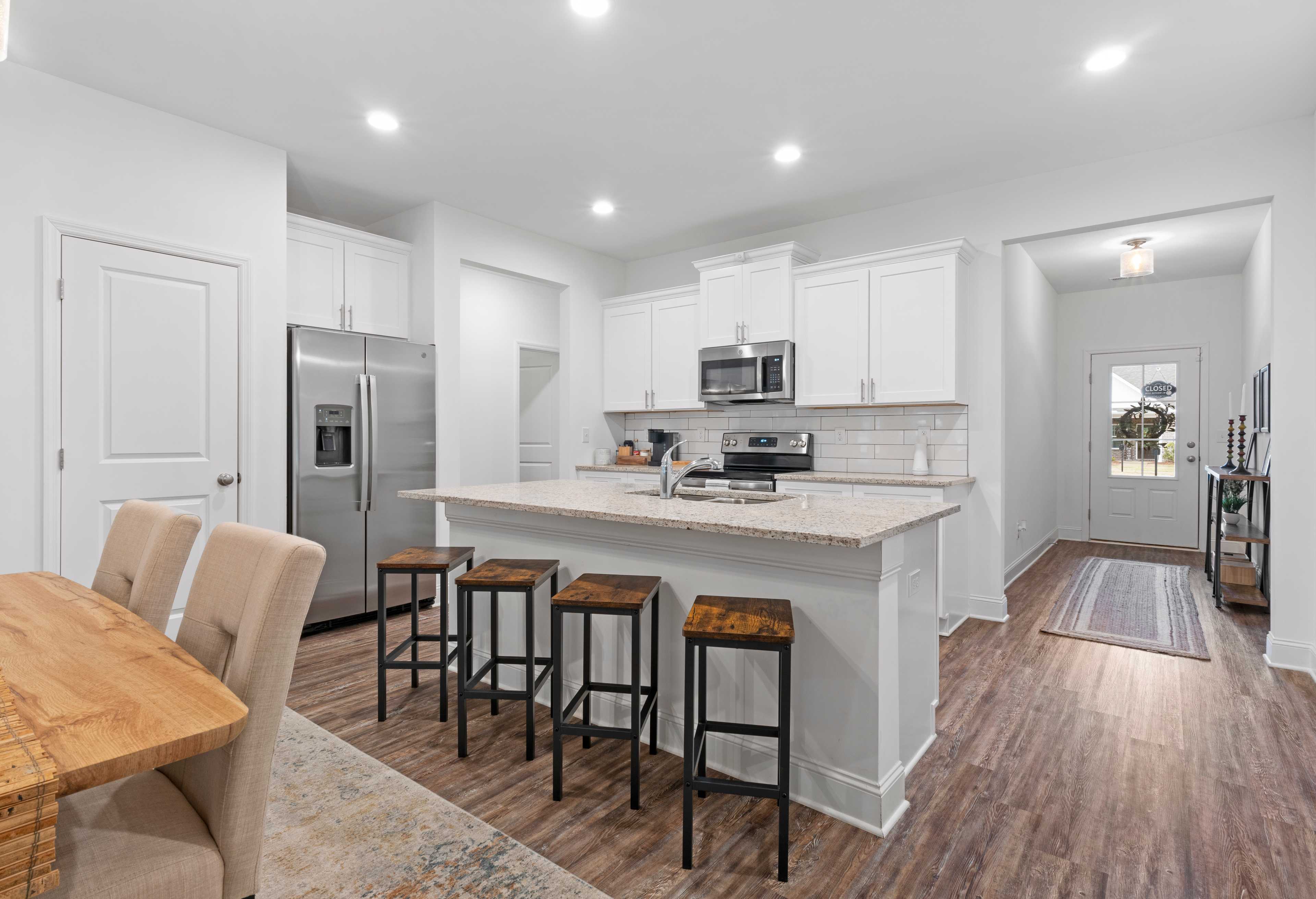 Spacious open-concept kitchen and dining in The Cumberland with white cabinets, large island, stainless steel appliances